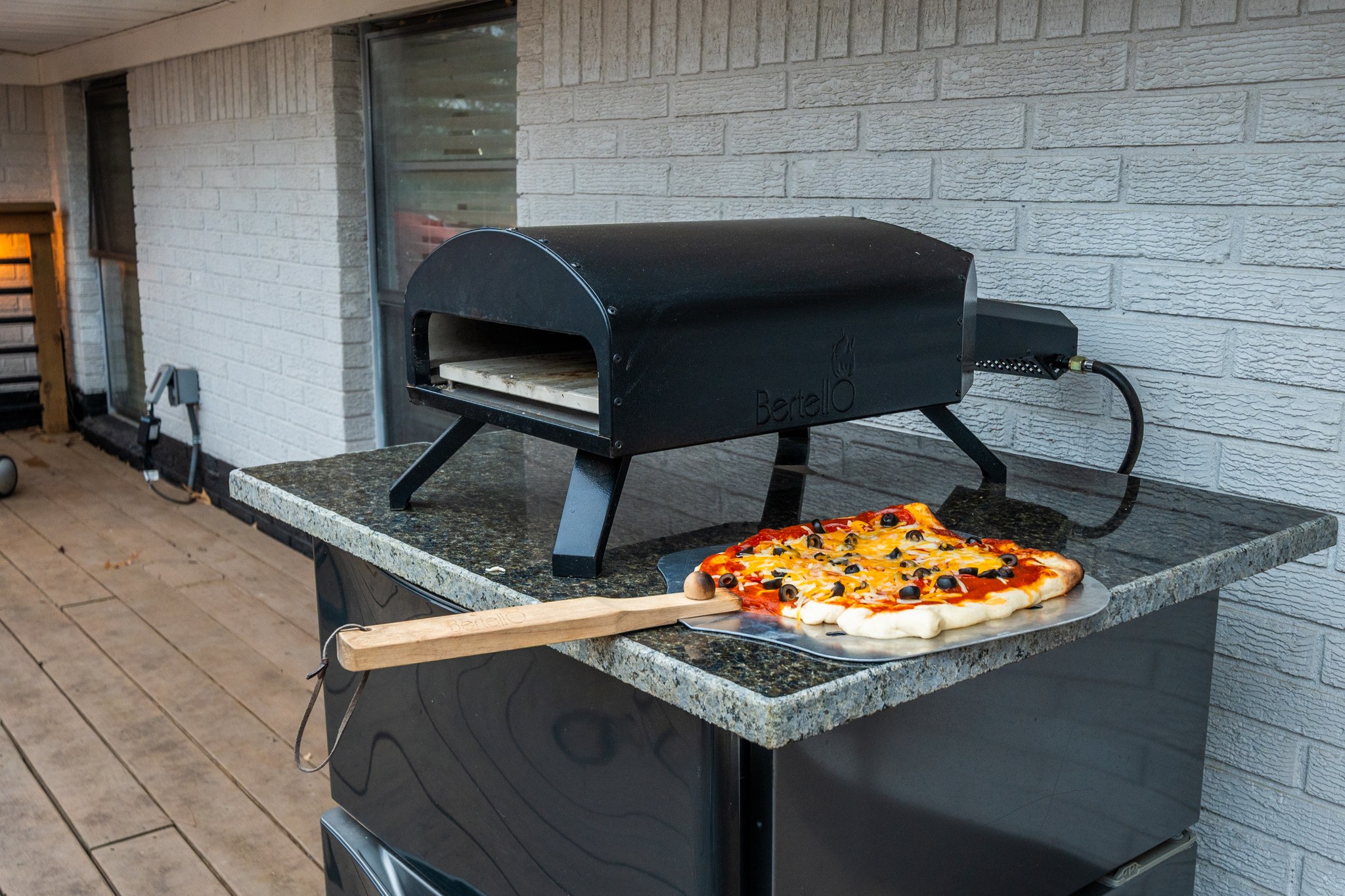 Fire the pizza oven up on the patio — homemade pies, ninety seconds each, and a line forming for the next one.