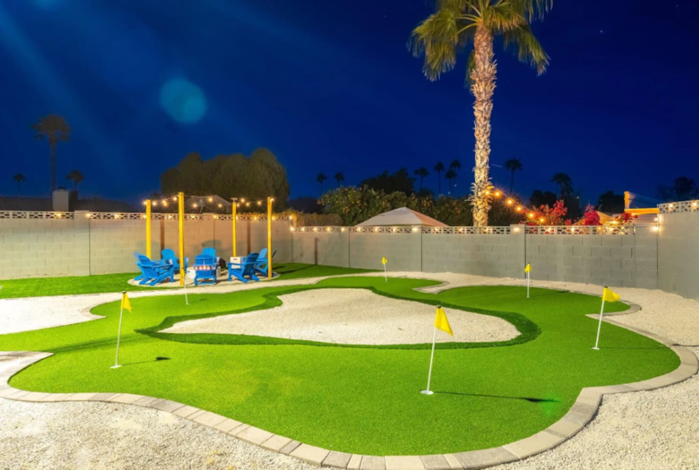 A backyard putting green under string lights and palm trees, because vacation should include a few rounds of mini golf before bed. Multiple holes mean the whole group can play at once.
