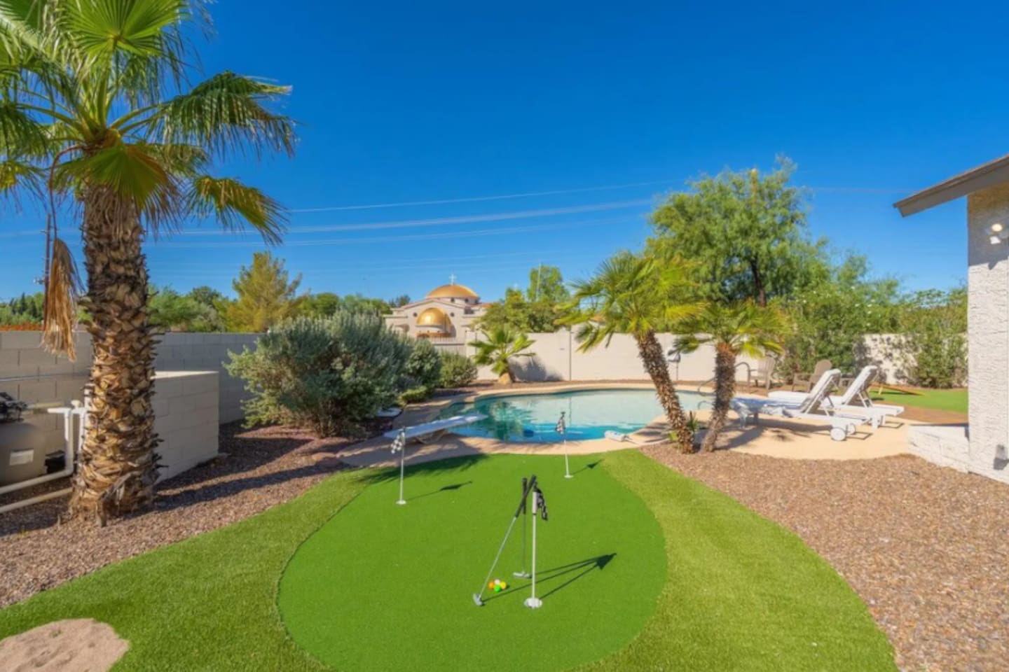 Luxury backyard oasis with resort-style pool, putting green, lounge areas, and meticulously landscaped grounds.