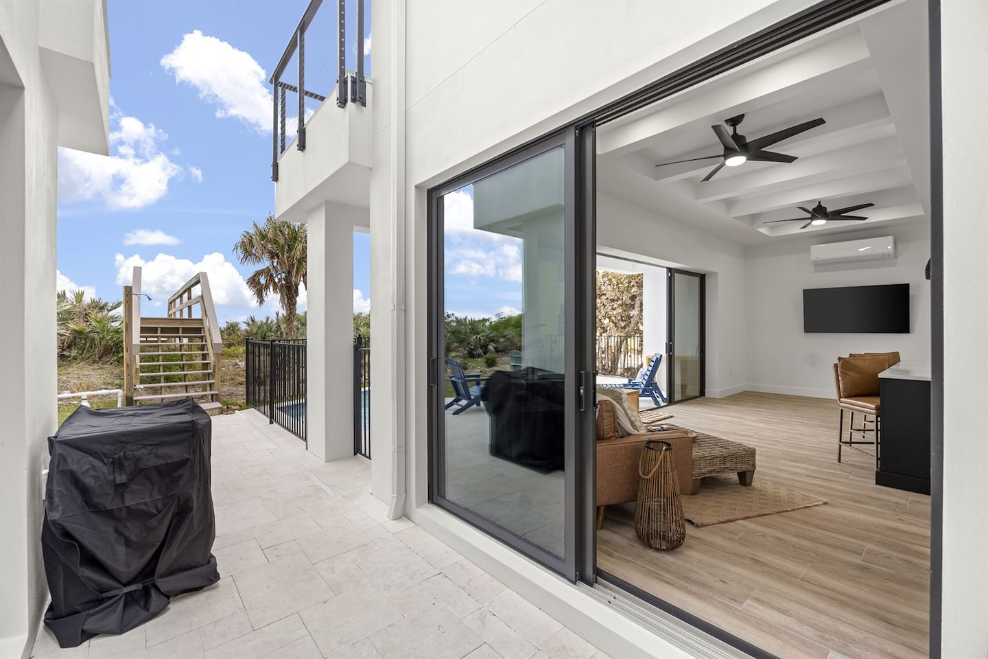Step into this outdoor oasis featuring a bridge leading to the sea, a spacious terrace with elegant flooring, and a sleek glass side door offering seamless access to the indoors, perfect for enjoying both outdoor and indoor living.