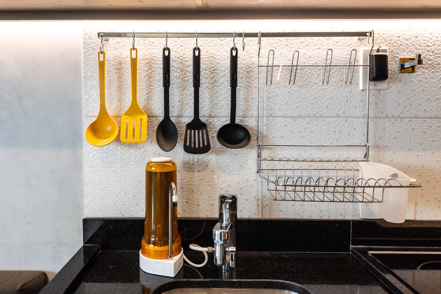 Pia com utensílios de cozinha organizados, facilitando sua experiência no apartamento.