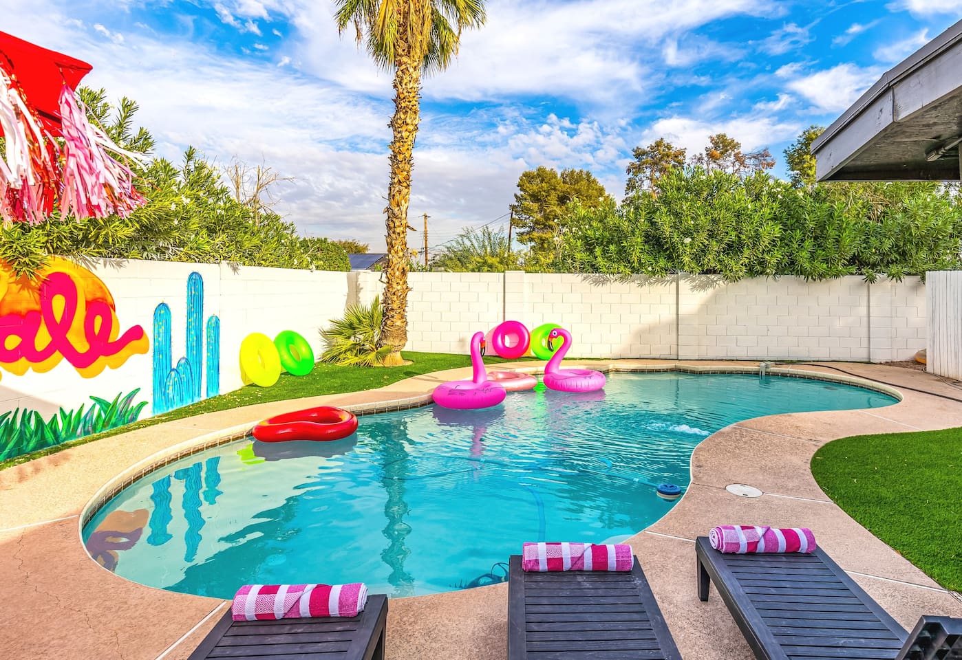Bright pool floats, mural art, and palm trees create the ultimate backyard playground for friends and family.