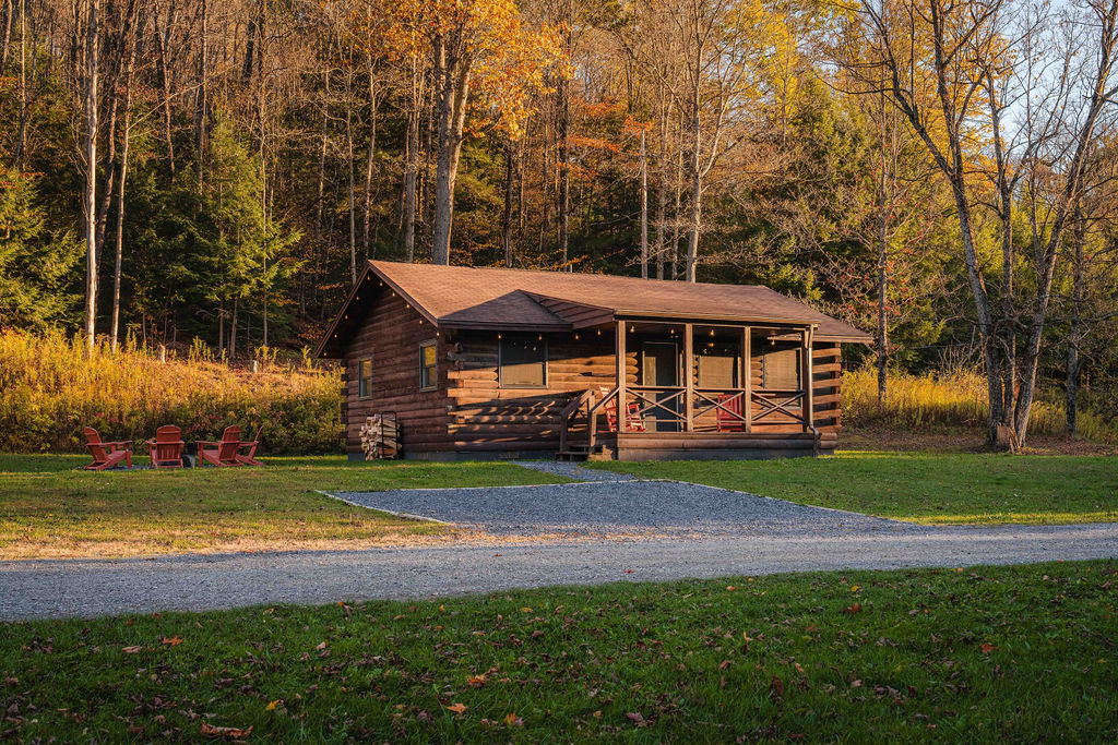 Your private log cabin hideaway, surrounded by trees with red Adirondack chairs ready for starlit nights.