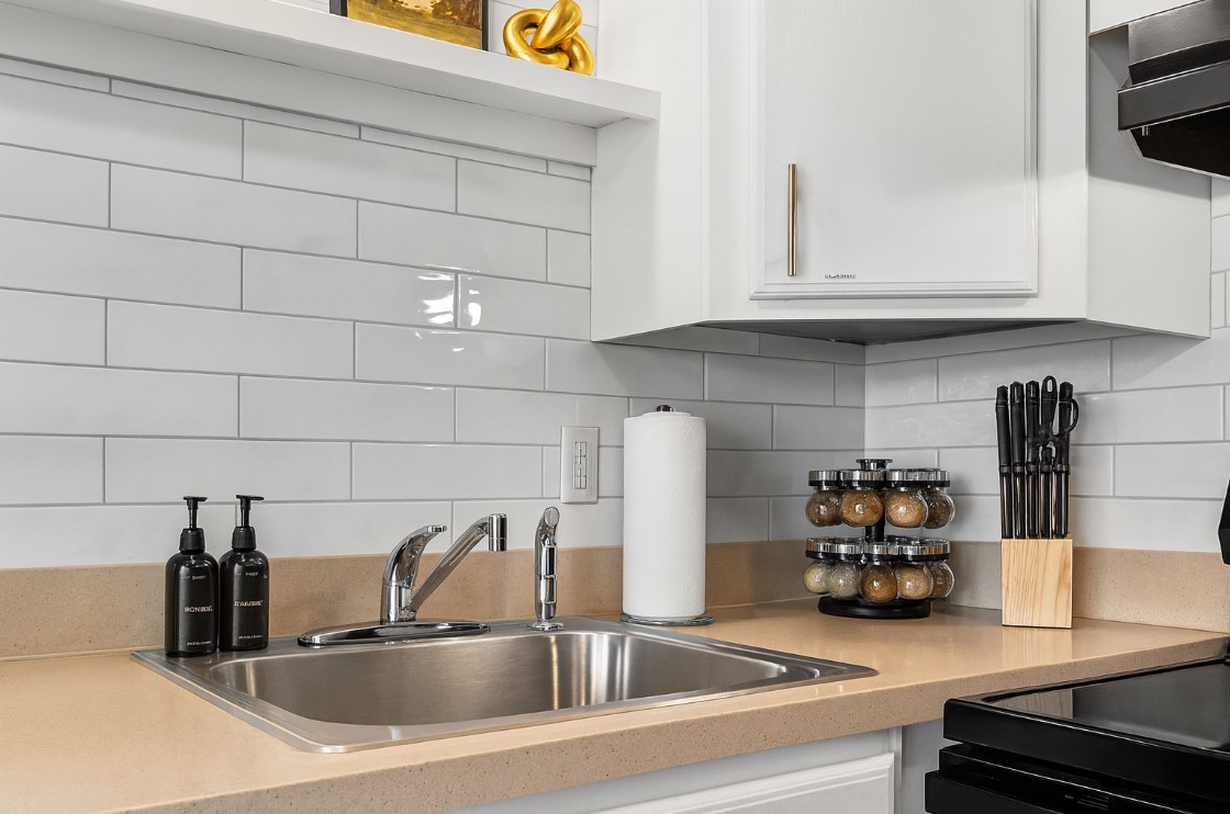 Modern kitchen with sleek countertops, subway tile backsplash, and fully stocked essentials including knives, spices, and cooking basics—perfect for enjoying home-cooked meals during your stay
