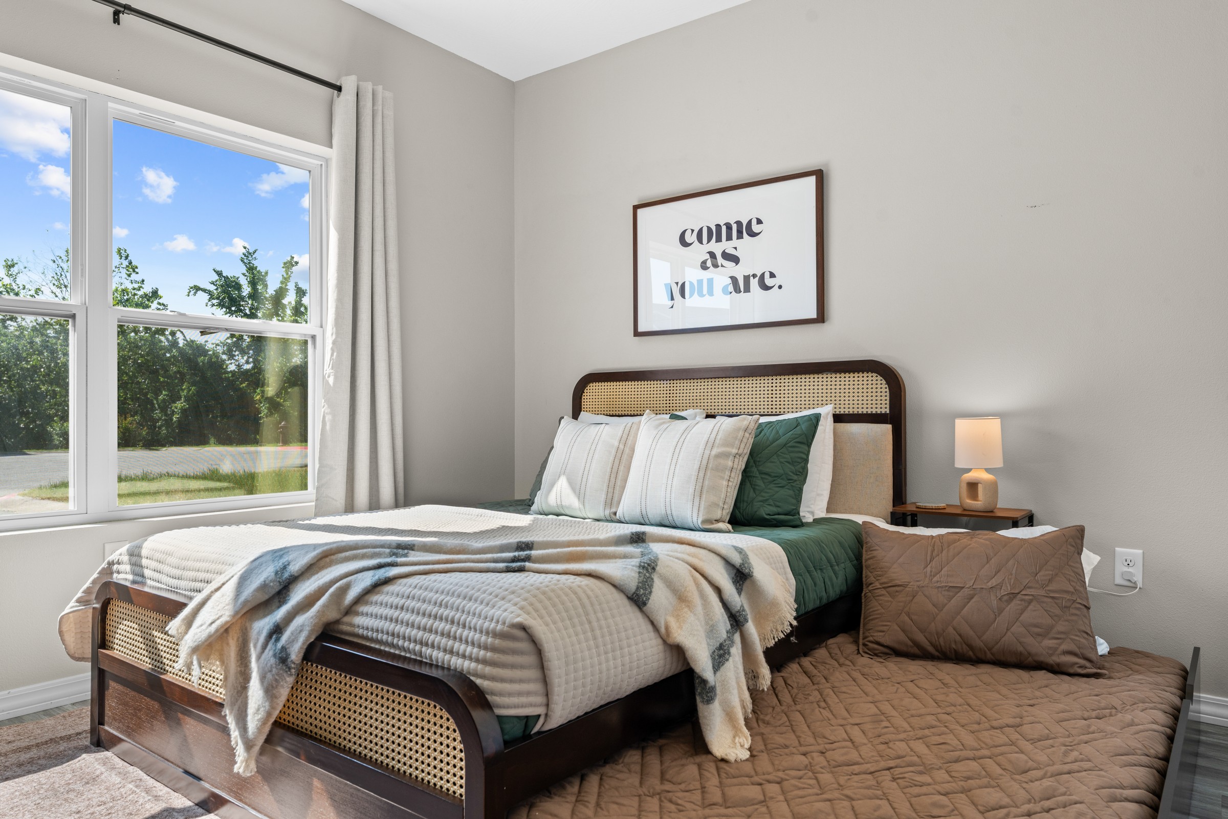 Queen bed with twin trundle in Bedroom 3. A cane headboard, soft linens and room for one more to sleep.