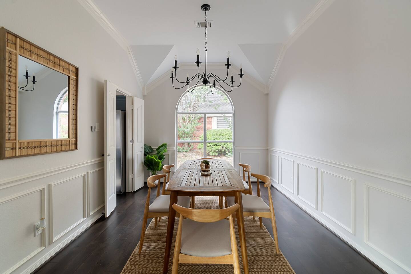 Enjoy a cozy dining area adorned with a wall mirror, inviting in the outdoor scenery through a window at the back.