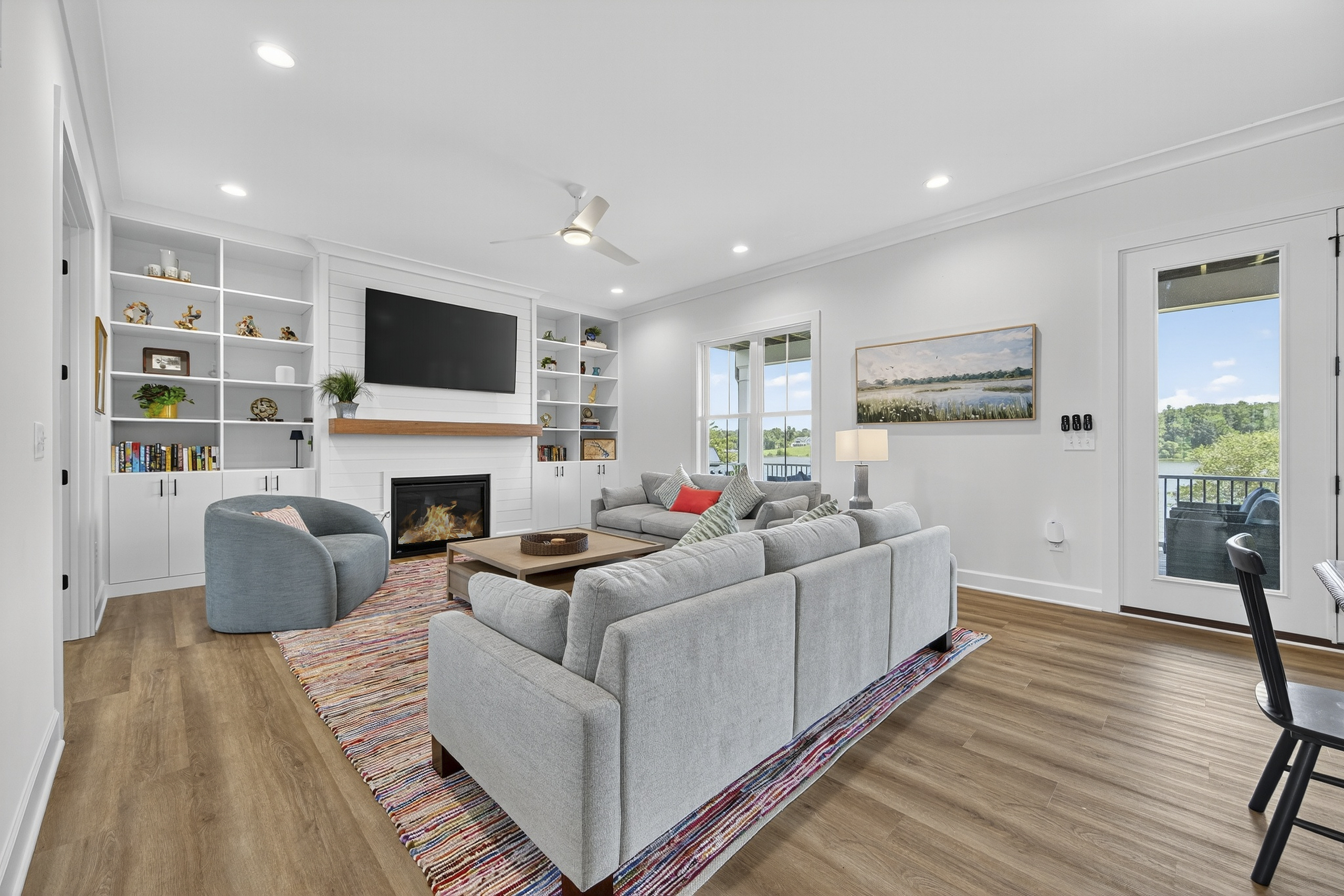 Bright and inviting living room with custom built-ins, a cozy fireplace, and large windows that frame the lake views—perfect for relaxing or entertaining.