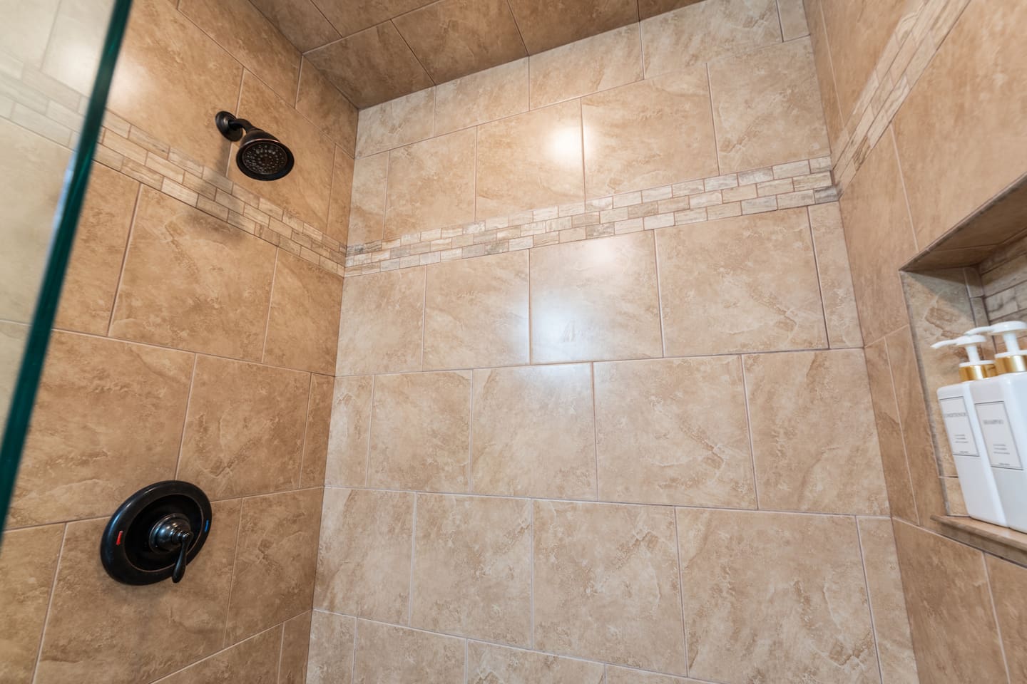 Enjoy a relaxing rinse in the modern tiled walk-in shower with premium bath products provided.