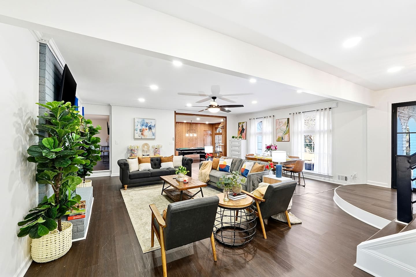 Warm and welcoming living room with two comfortable couches, two chairs, indoor plants, a cozy fireplace, and a TV powered by Google TV. Conveniently located as you walk through the front door and straight ahead from the primary side entrance. 