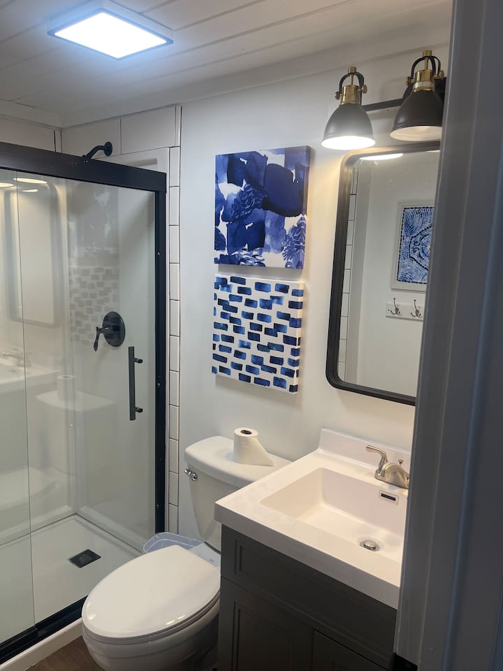 Step into this stylish bathroom featuring a sleek glass shower with black trim, modern vanity, and fun blue-themed decor. Thoughtfully designed for comfort and convenience, it's a fresh and functional space to start or end your day during your stay.