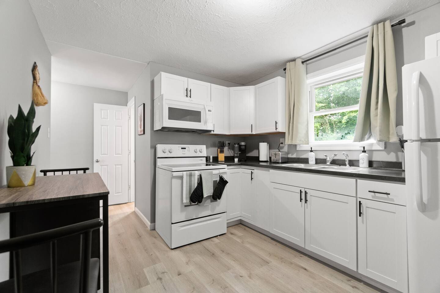 Fully equipped kitchen with modern appliances, complemented by a cozy dining area for two, perfect for meals at home.