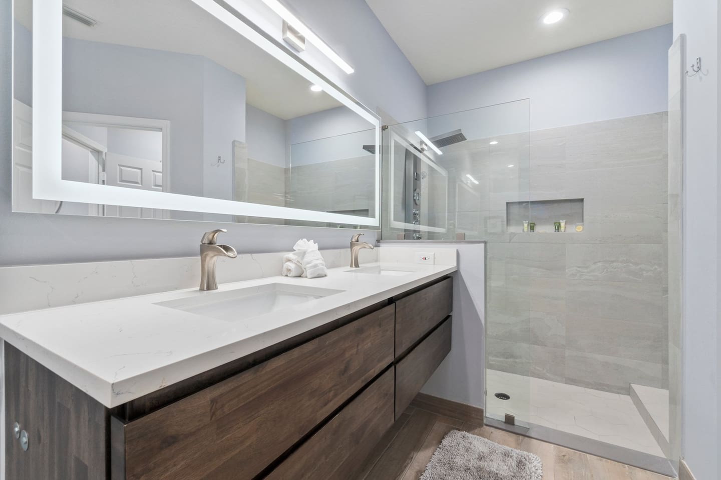 Modern bathroom with a large vanity, illuminated mirror, glass shower enclosure, and clean updated finishes.
