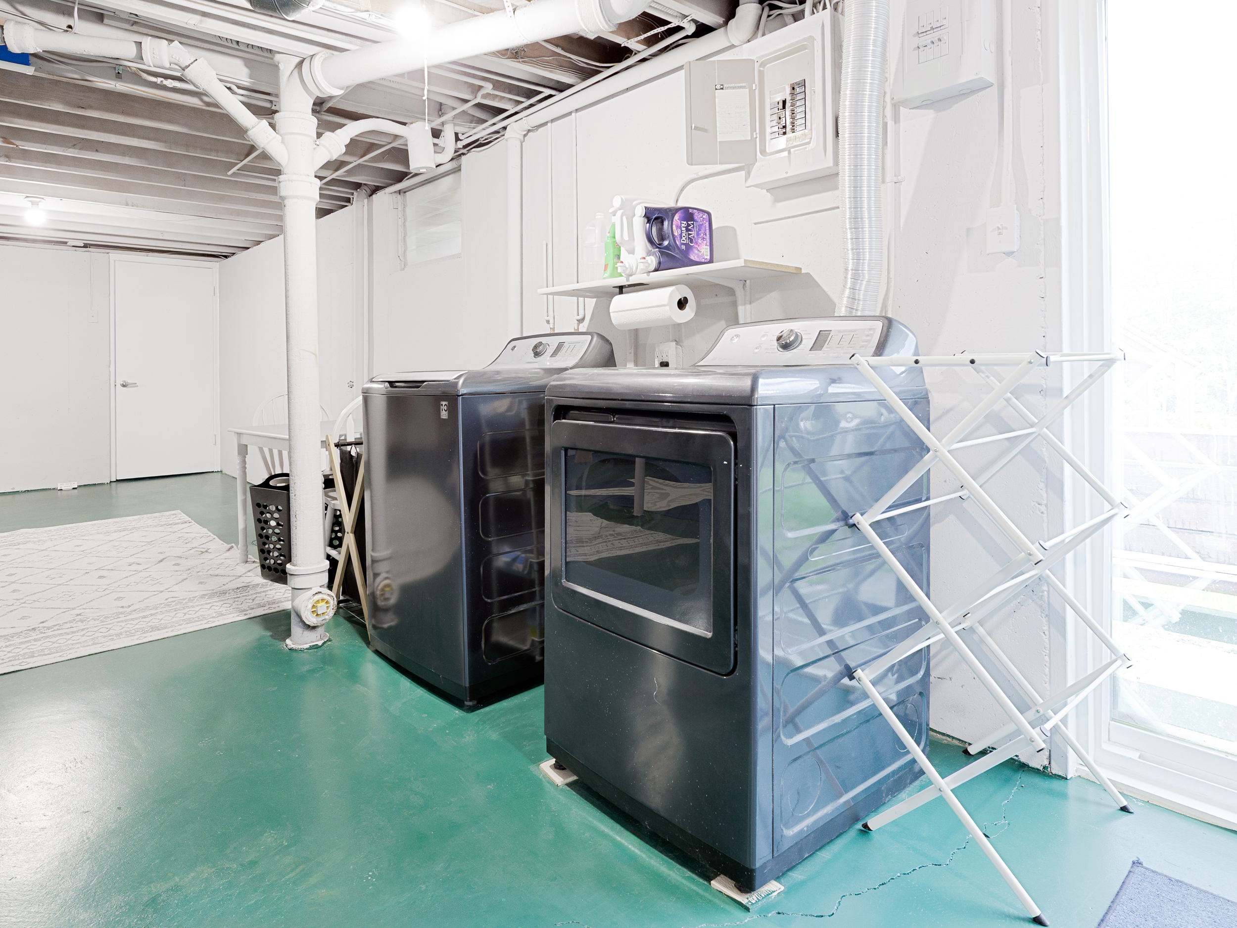 Basement laundry area equipped with washer, dryer, and convenient folding space.