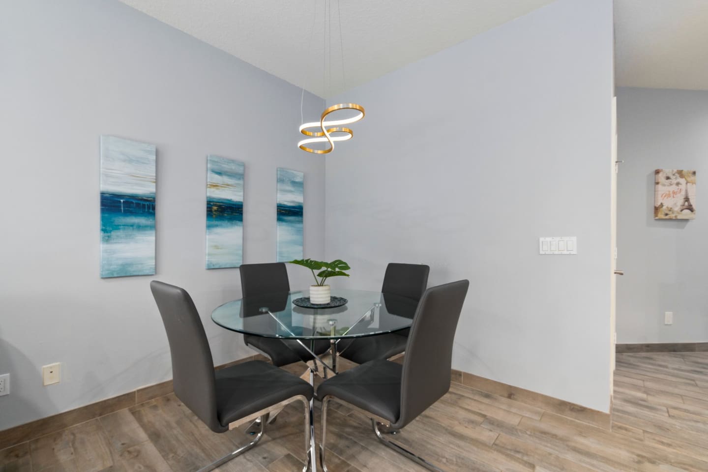 Modern dining area with a glass-top table, stylish chairs, and clean coastal-inspired decor.