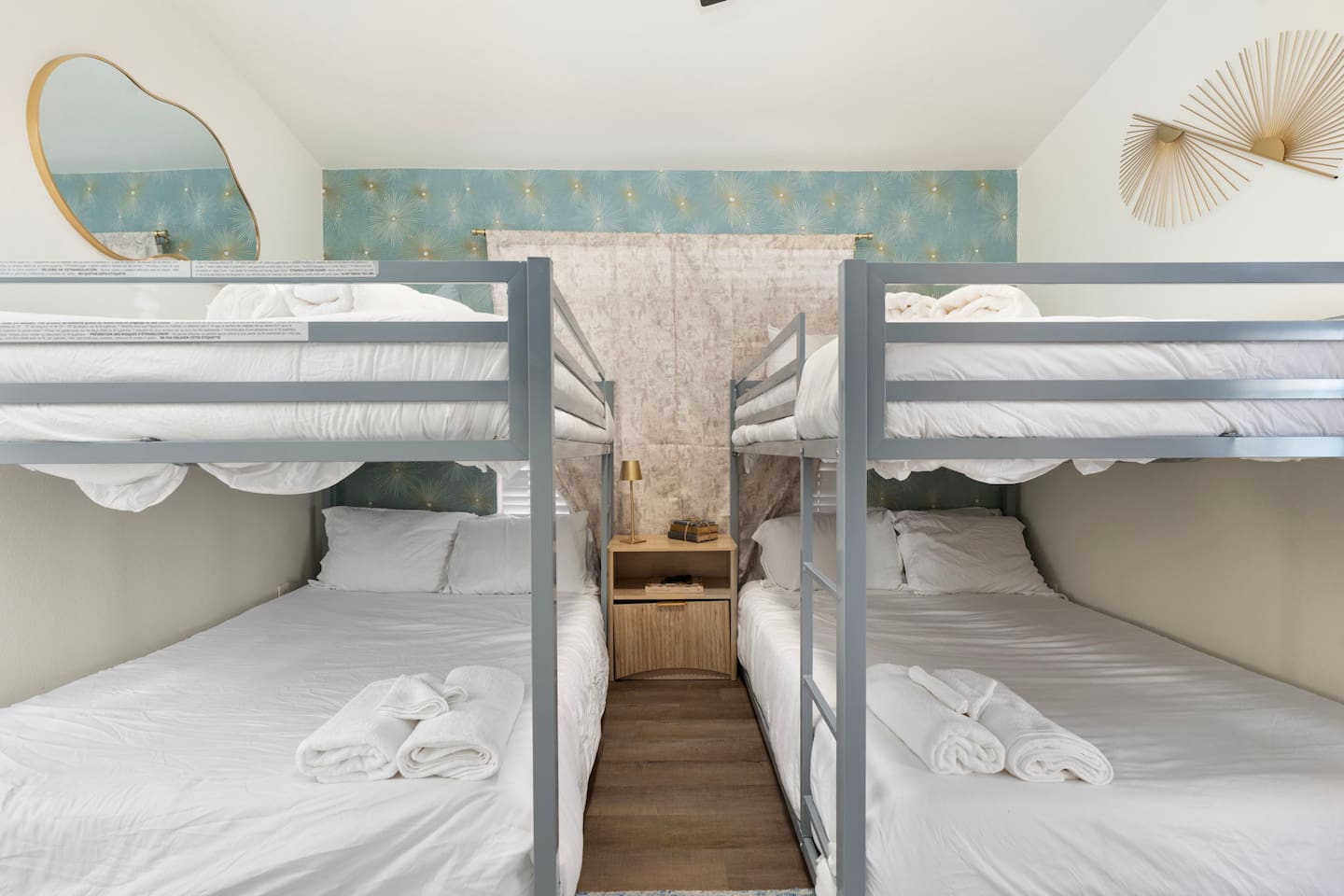 Quad bunk room with soft blue accents, white bedding, and modern finishes—sleeps four guests in comfortable style.