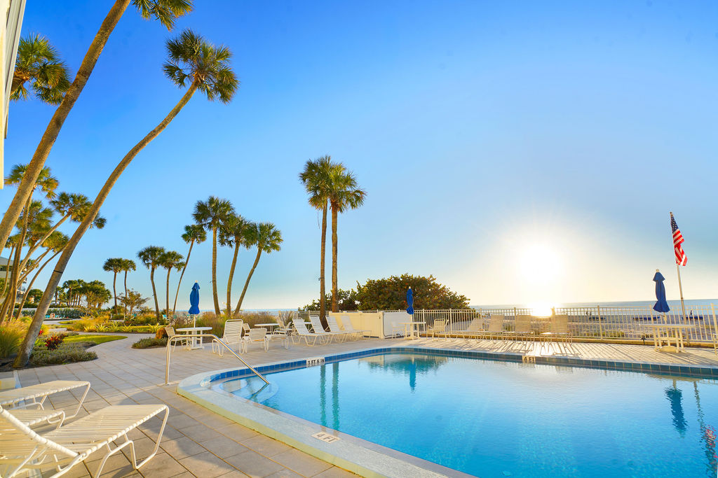 Resort-style oceanfront pool surrounded by palm trees, offering the perfect spot to relax during your beach vacation