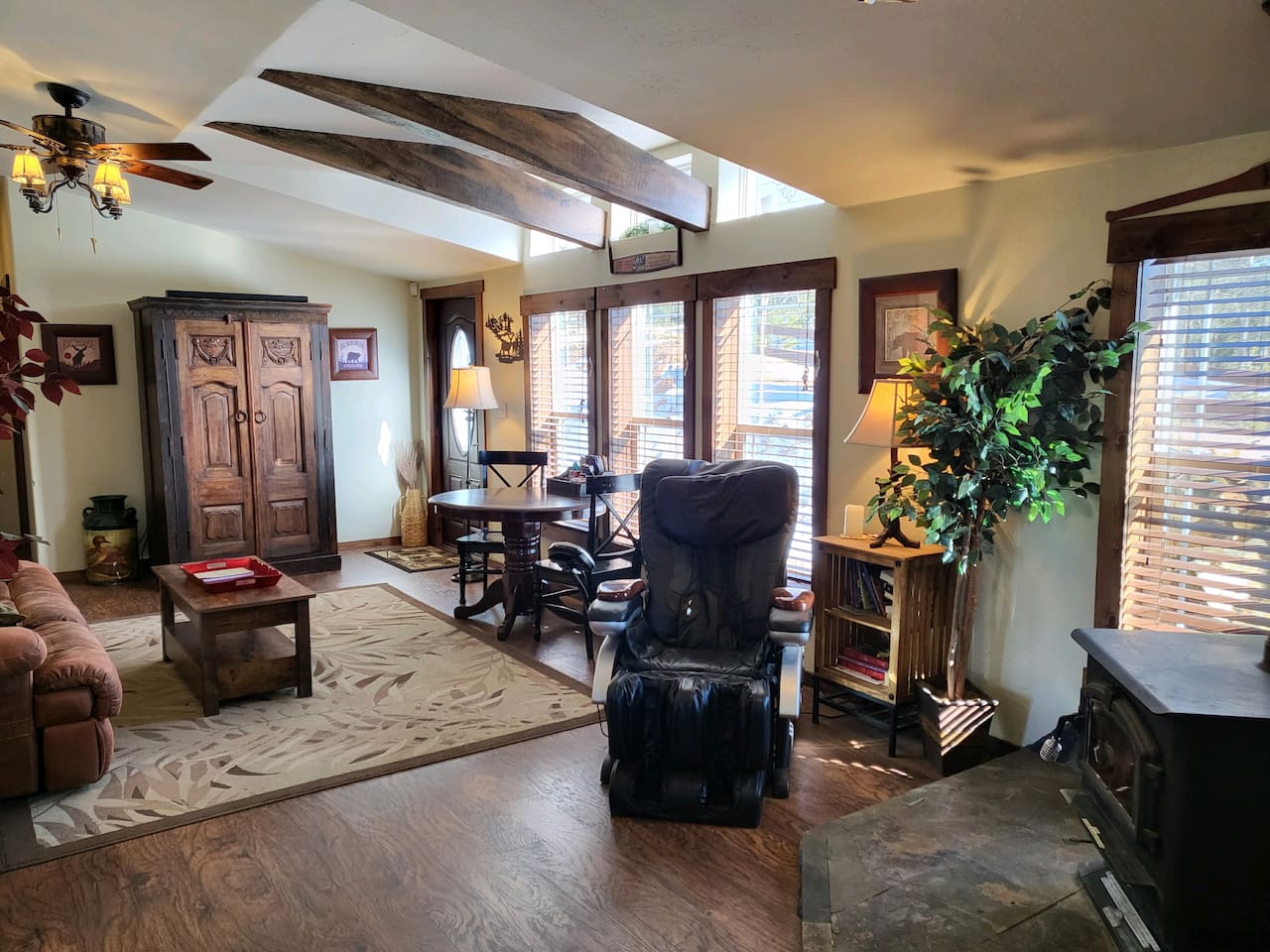 The second living area with a massage chair, wood stove, game table, and an armoire with TV, games, & DVDs