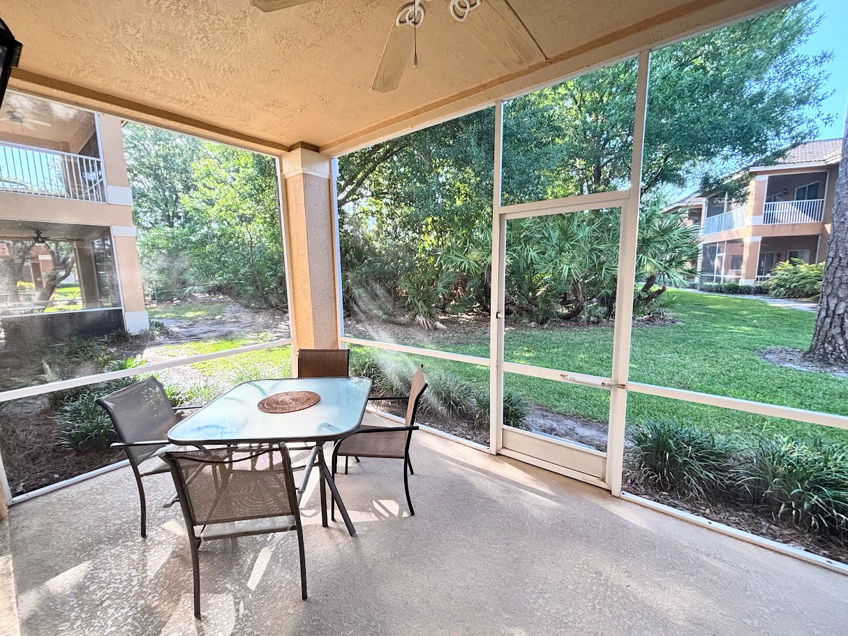 Private screened patio with outdoor seating and peaceful views of the surrounding green space.