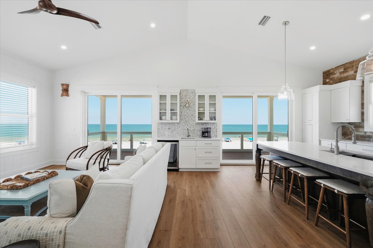 The top floor main level living room is open to the kitchen and features a coffee bar, wet bar with a beverage cooler, and direct access to the top level deck.