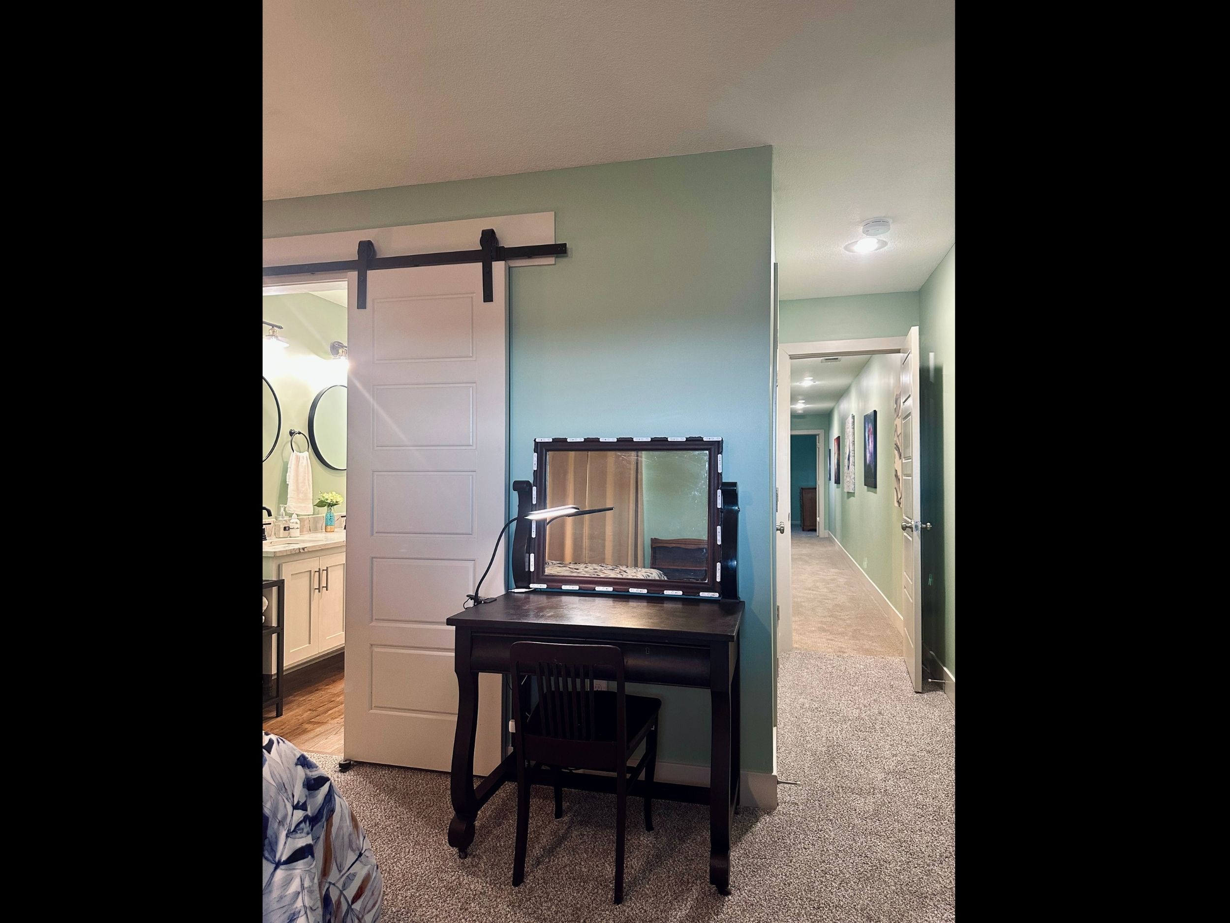 Primary suite workspace featuring a versatile desk with lamp, designed to function comfortably as both a work station and vanity.