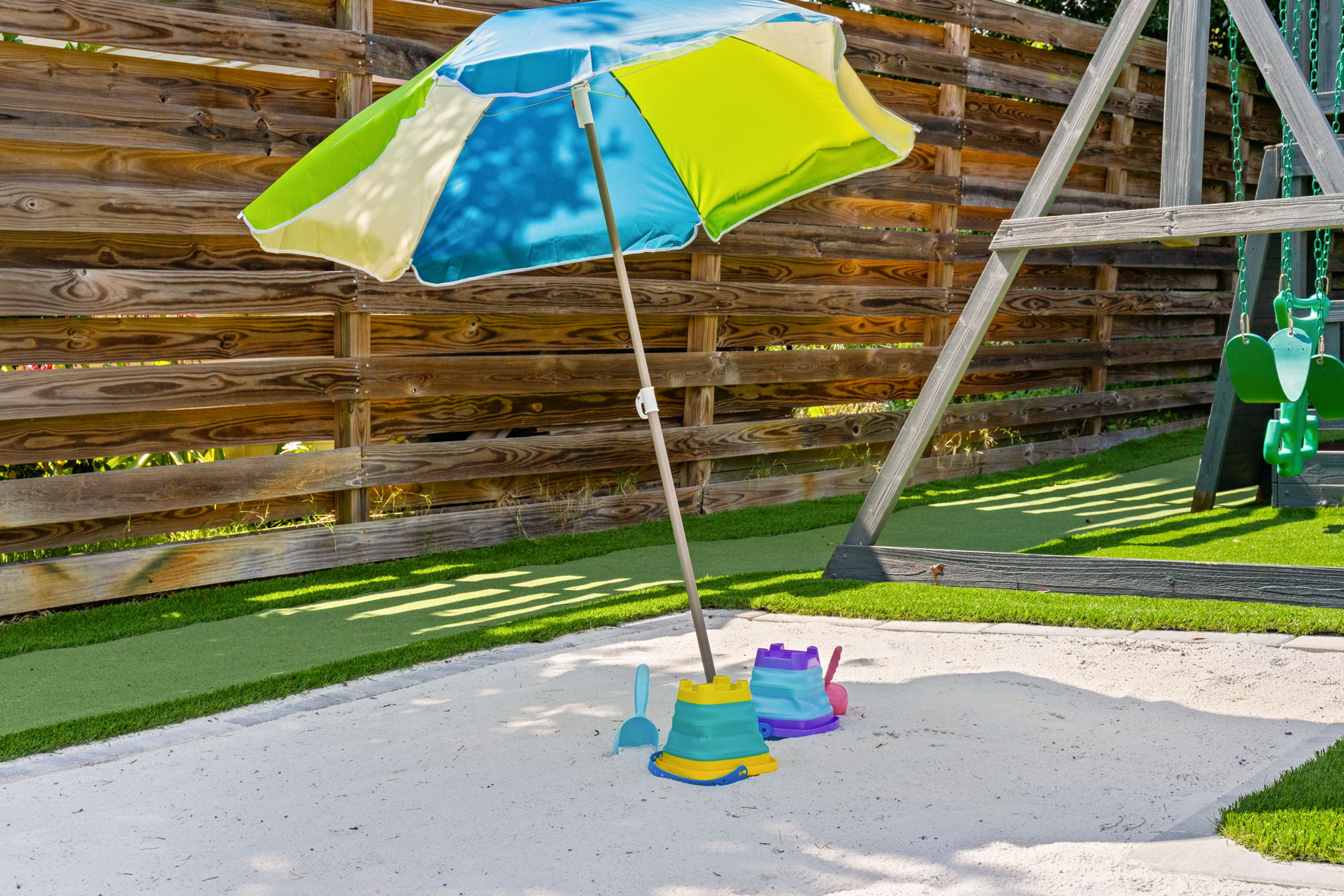A dedicated backyard sand bunker for the kids! Complete with clean sand, fun beach toys, and a colorful shade umbrella right next to the playset. Perfect for hours of safe, outdoor imagination and play.