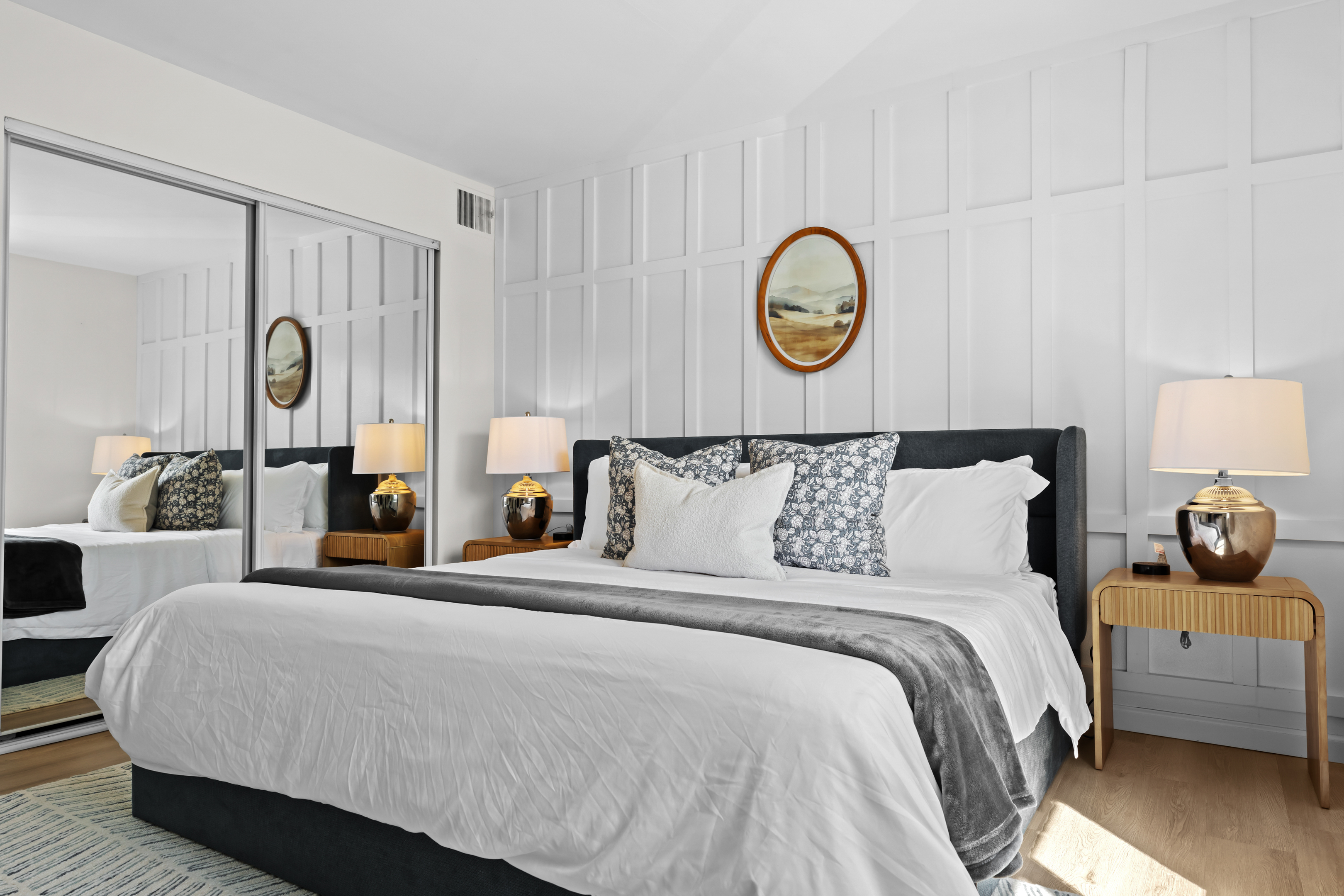 Rest well in a beautifully designed bedroom with a comfortable queen bed, mirrored closet doors, and warm lighting.