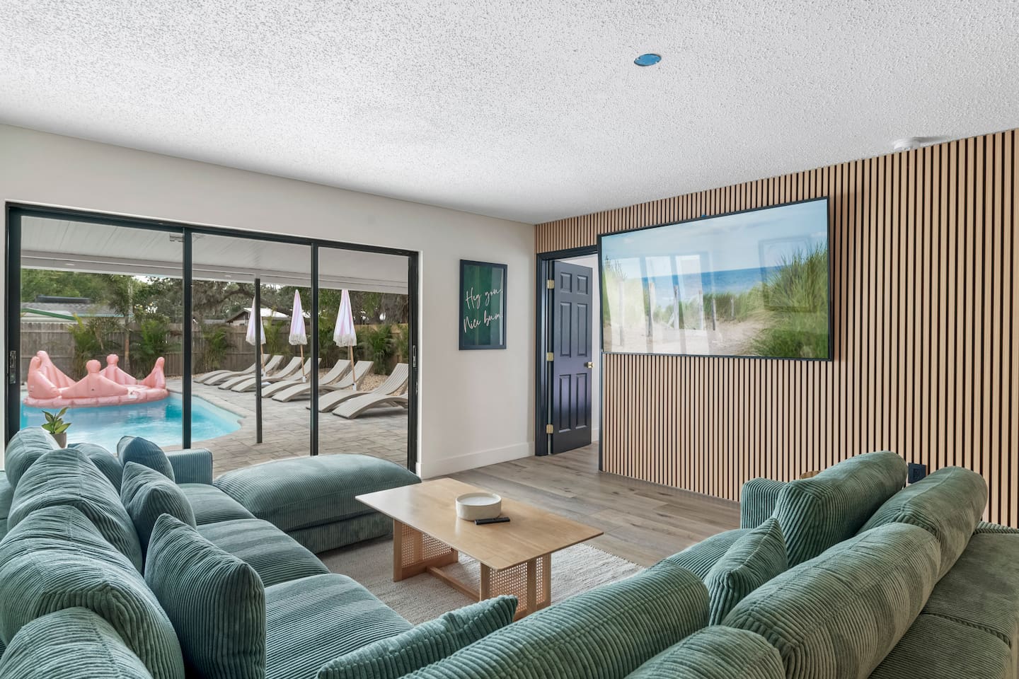 Stylish Living Room with 85-Inch TV. Acoustical accent wall, open to the kitchen and the pool 