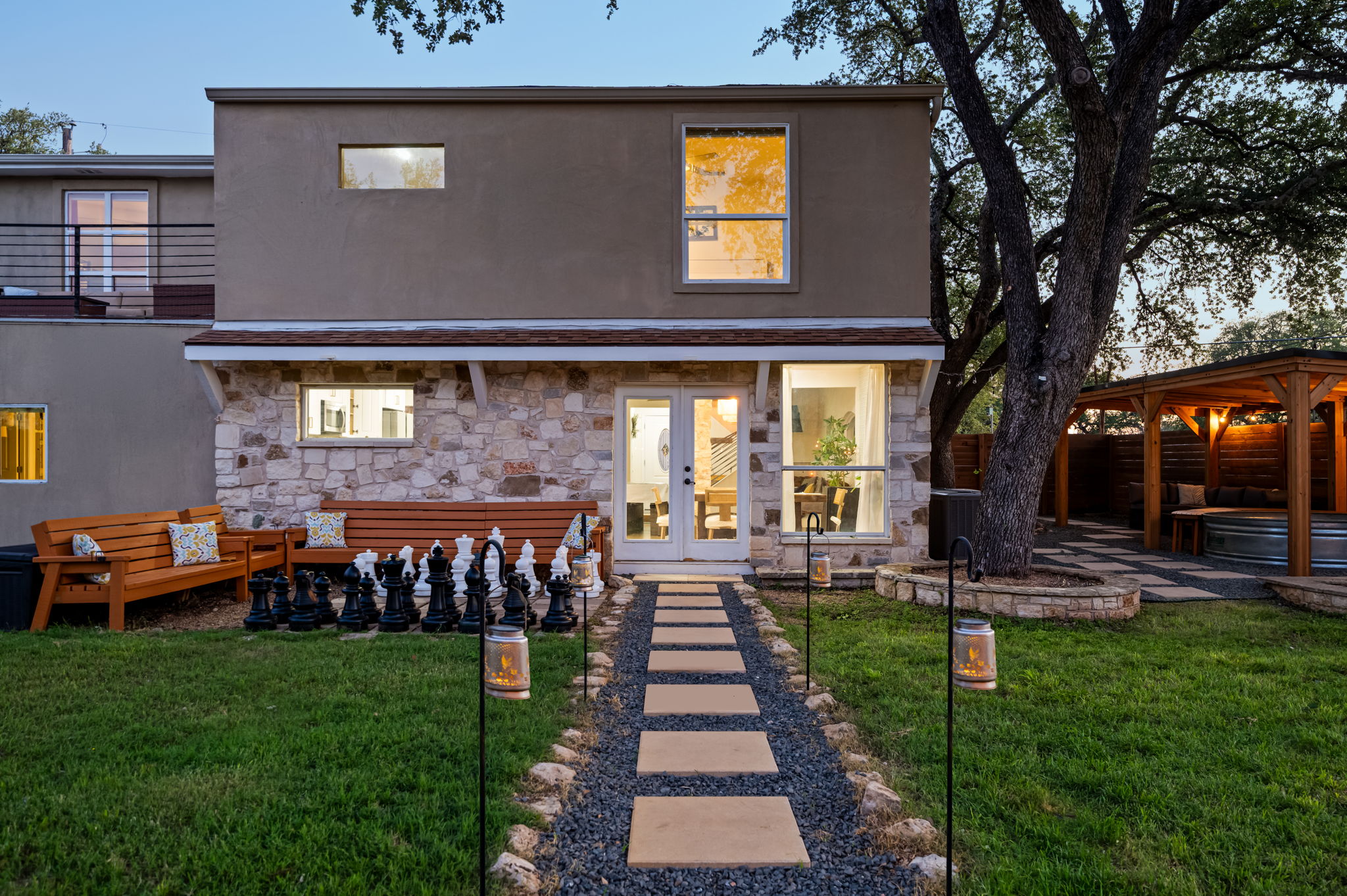 Step into a fully fenced backyard oasis featuring giant outdoor chess, cozy lounge seating, a covered hangout area, and inviting evening lighting. Designed for fun, relaxation, and unforgettable group gatherings.