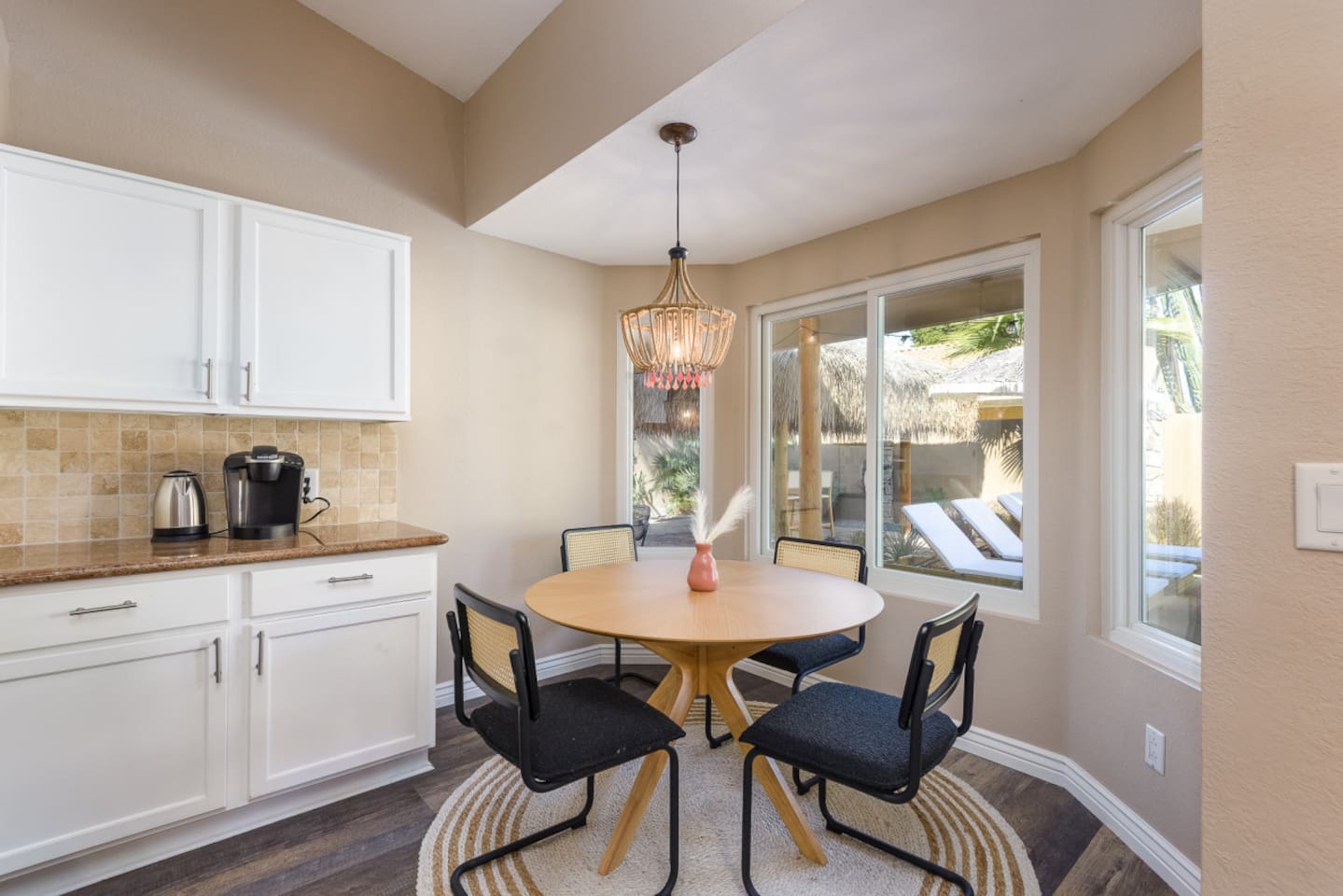 Dining nook with round table seating, bay windows, and views out to the pool area for meals or morning coffee.
