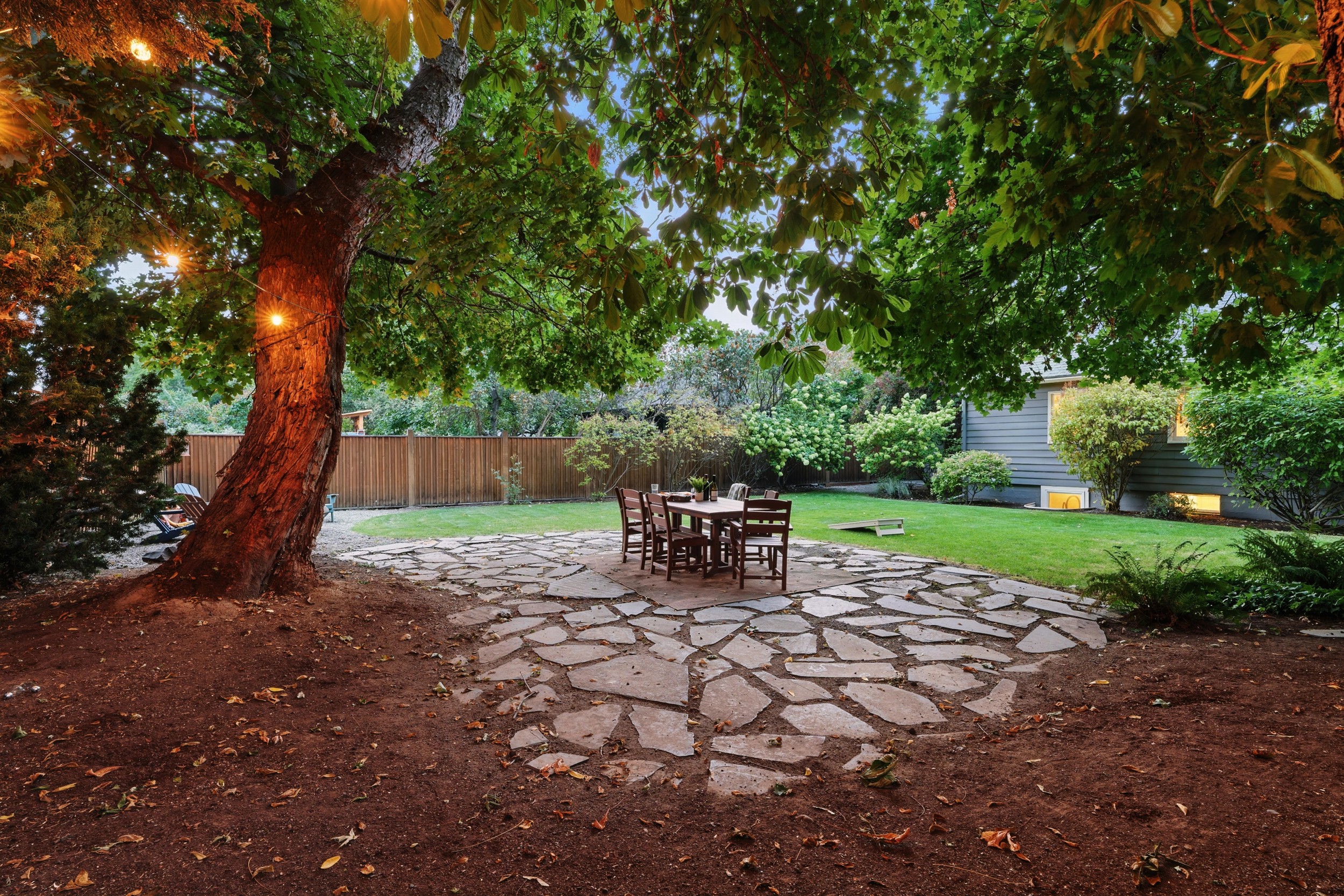 Large backyard with a park-like setting, outdoor dining for 6, corn hole, and 6 lounge chairs gathered around the fire table (propane provided)