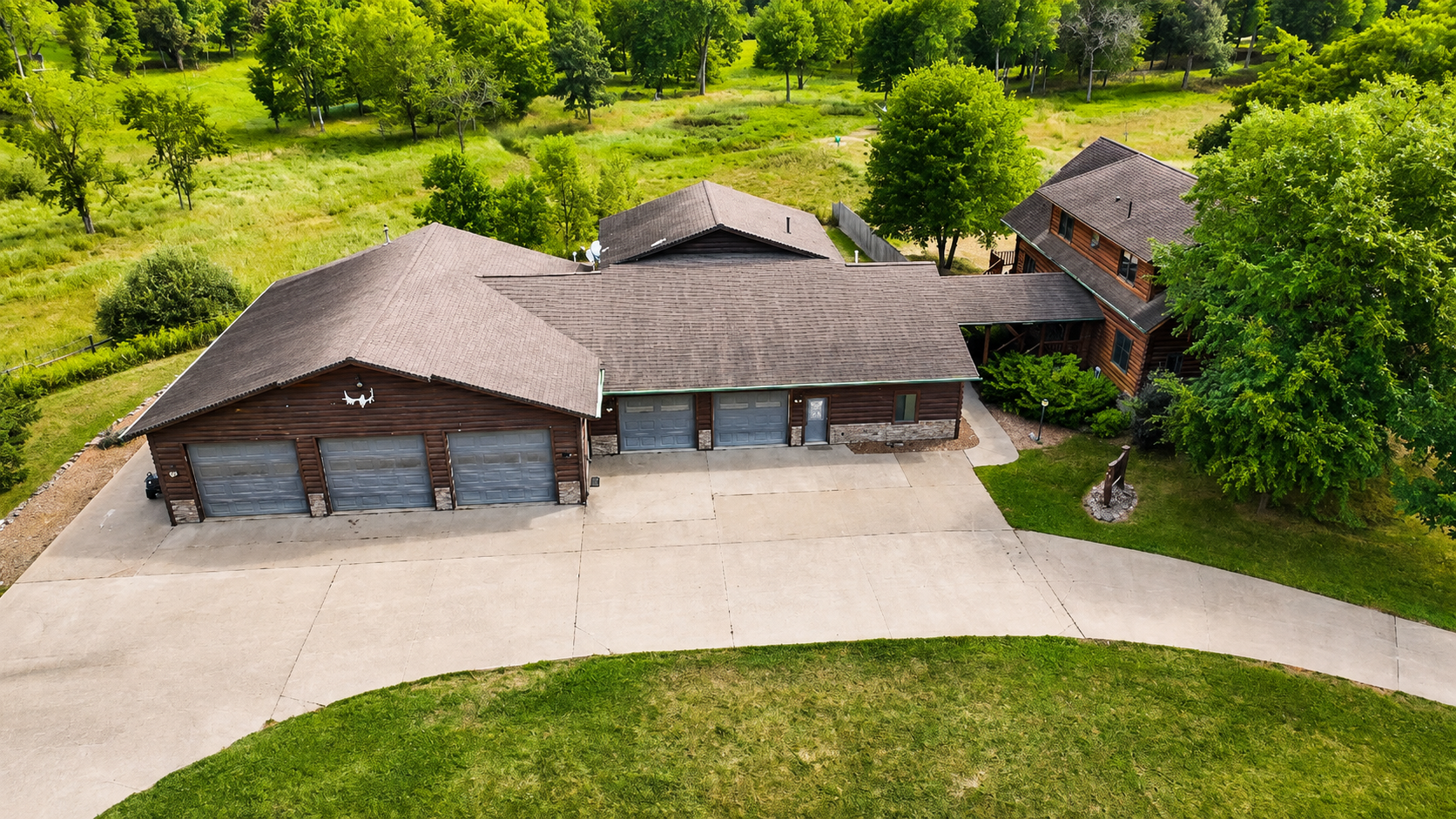 Aerial view of the property entrance, buildings, driveway, and parking area, showing the generous space available for larger groups traveling with multiple vehicles and outdoor gear.