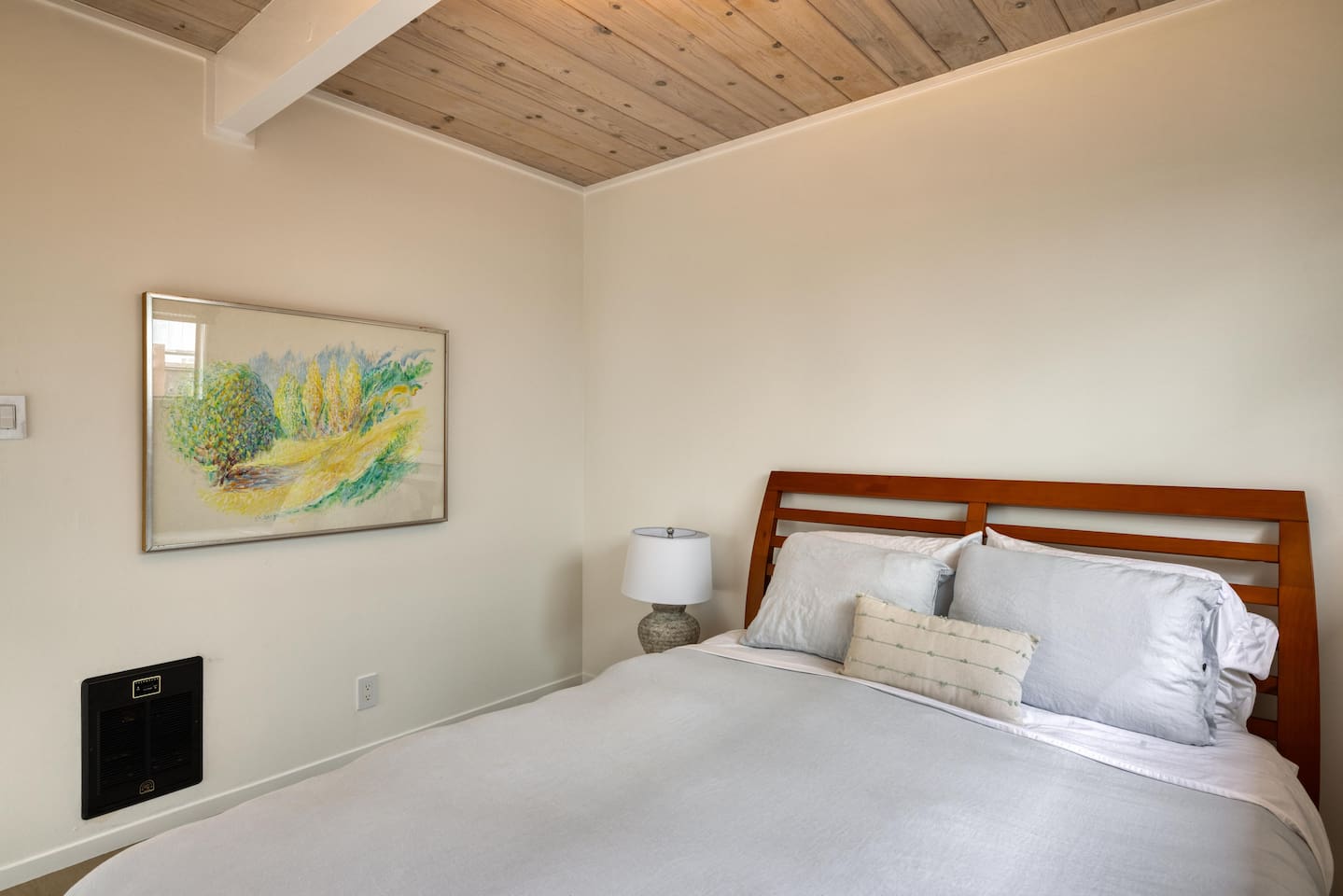 - Cozy bedroom with queen bed and crisp white linens for restful nights  
- Wooden headboard and bedside lamp offer a touch of classic style  
- Minimalist decor with bright artwork creates a calming atmosphere  
