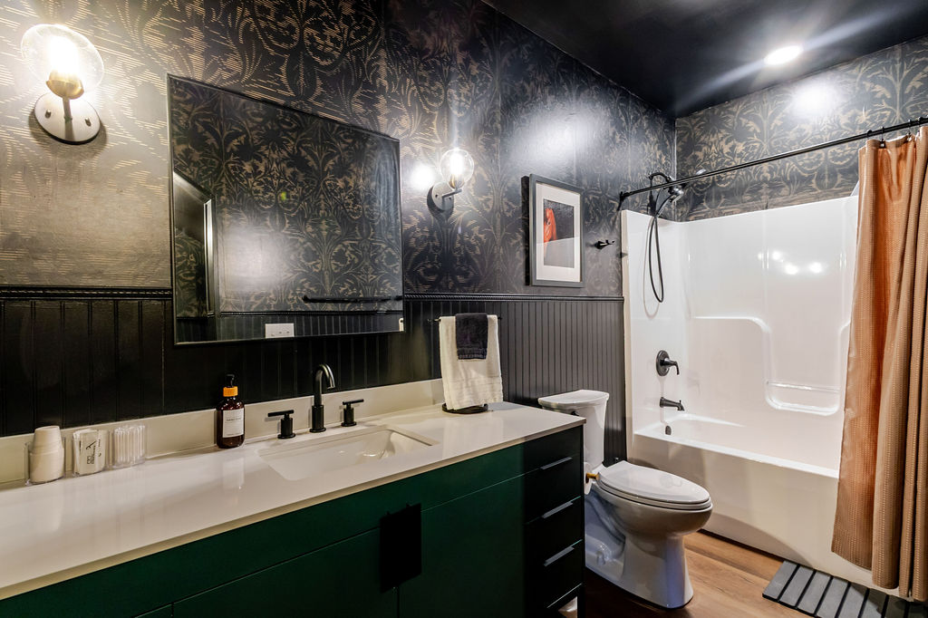 Wrapped in dark, tailored finishes and soft lighting, this shared bath channels boutique-hotel luxury — a polished retreat for guests to refresh, reset, and prepare for the next chapter of the