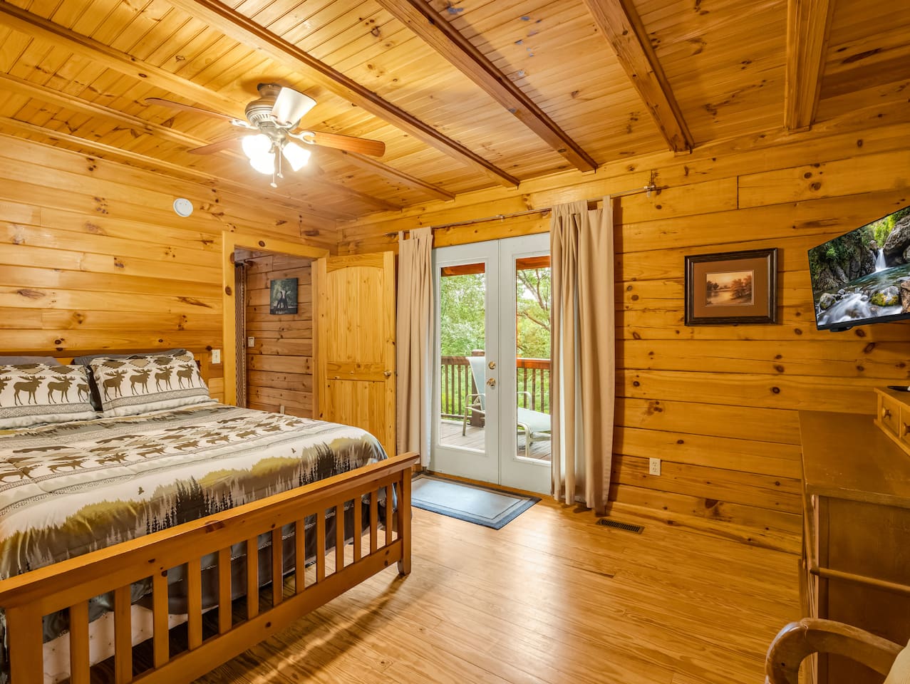 Another view of main level bedroom, showcasing a comfortable double bed and convenient deck access through French doors 