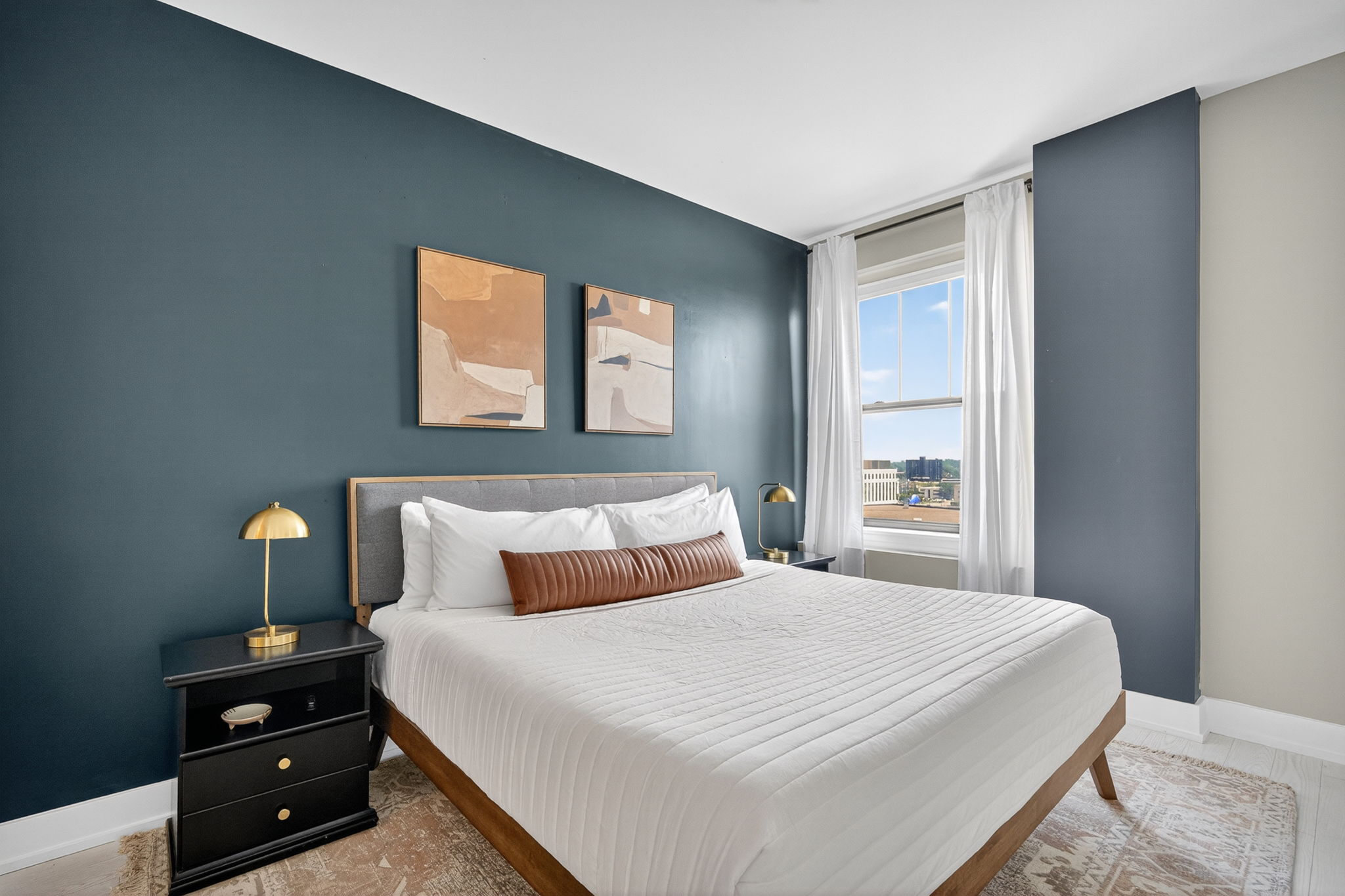 Spacious bedroom with a plush king bed, layered linens, and a calming green accent wall. Designed for restful nights and stylish mornings.