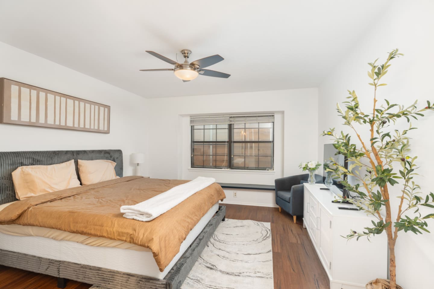 Bedroom view with upholstered bed and warm natural tones.