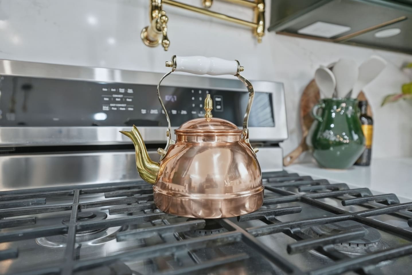 Another view of the gas stove with a charming copper kettle and elegant brass pot filler—great for effortless cooking.