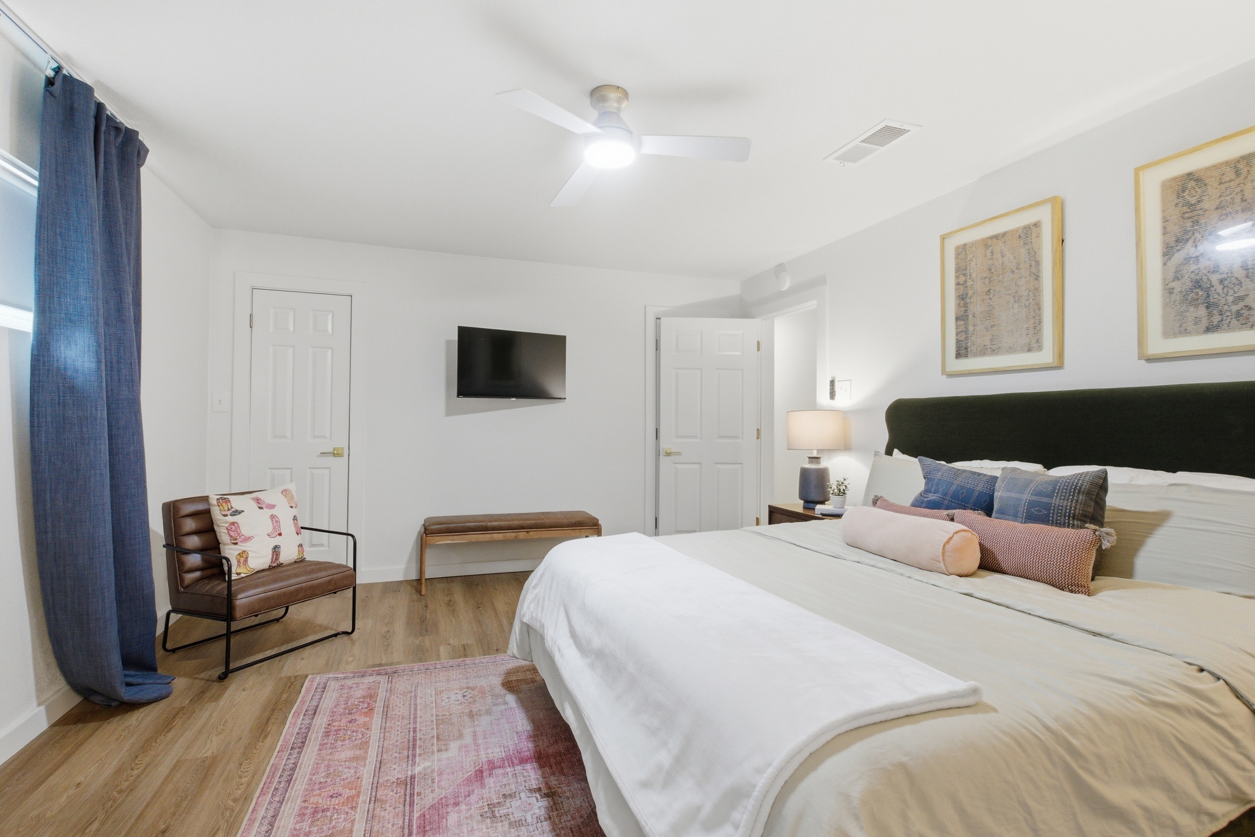 King Bed suite wide-angle with Smart TV, ceiling fan, and ample closet space. Room-darkening shades and extra pillows and blankets provided. High-speed Wi-Fi throughout.