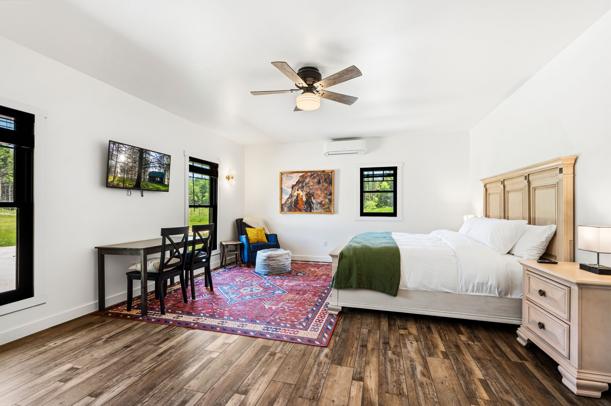 Retreat to the second king bedroom, a spacious suite with a smart-TV, cozy sitting area, and a small dining table set beneath sunny windows.