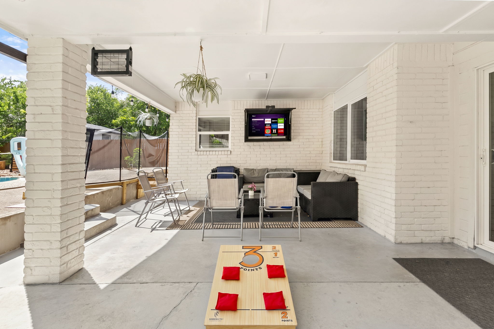 Your private outdoor hangout. Enjoy the covered patio with comfortable seating, outdoor TV, cornhole, and easy access to the backyard and pool—perfect for relaxing with family and friends.
