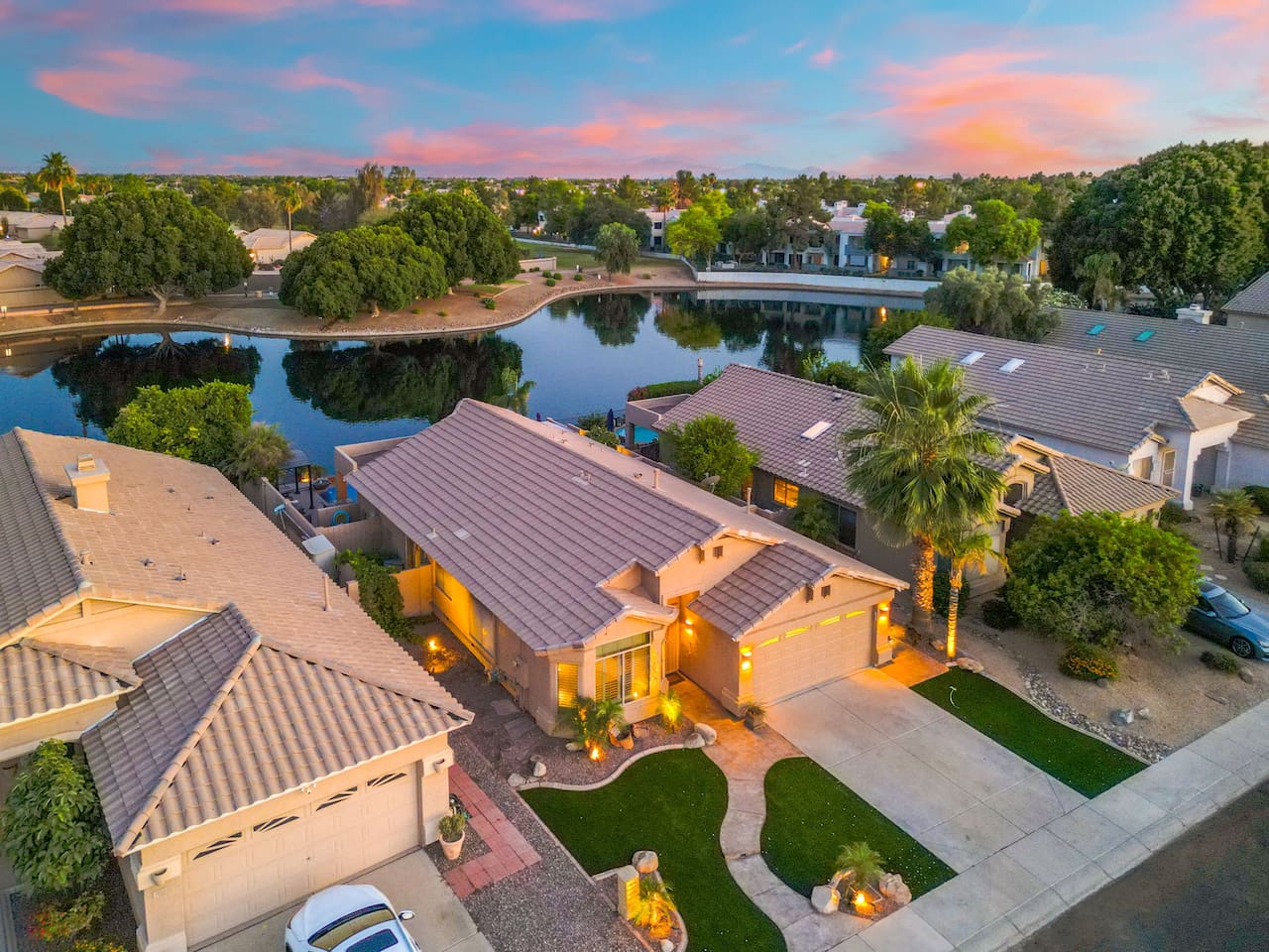 Pull up to a beautifully landscaped front entrance with manicured turf, swaying palms, and warm exterior lighting — the welcome begins before you even step inside.