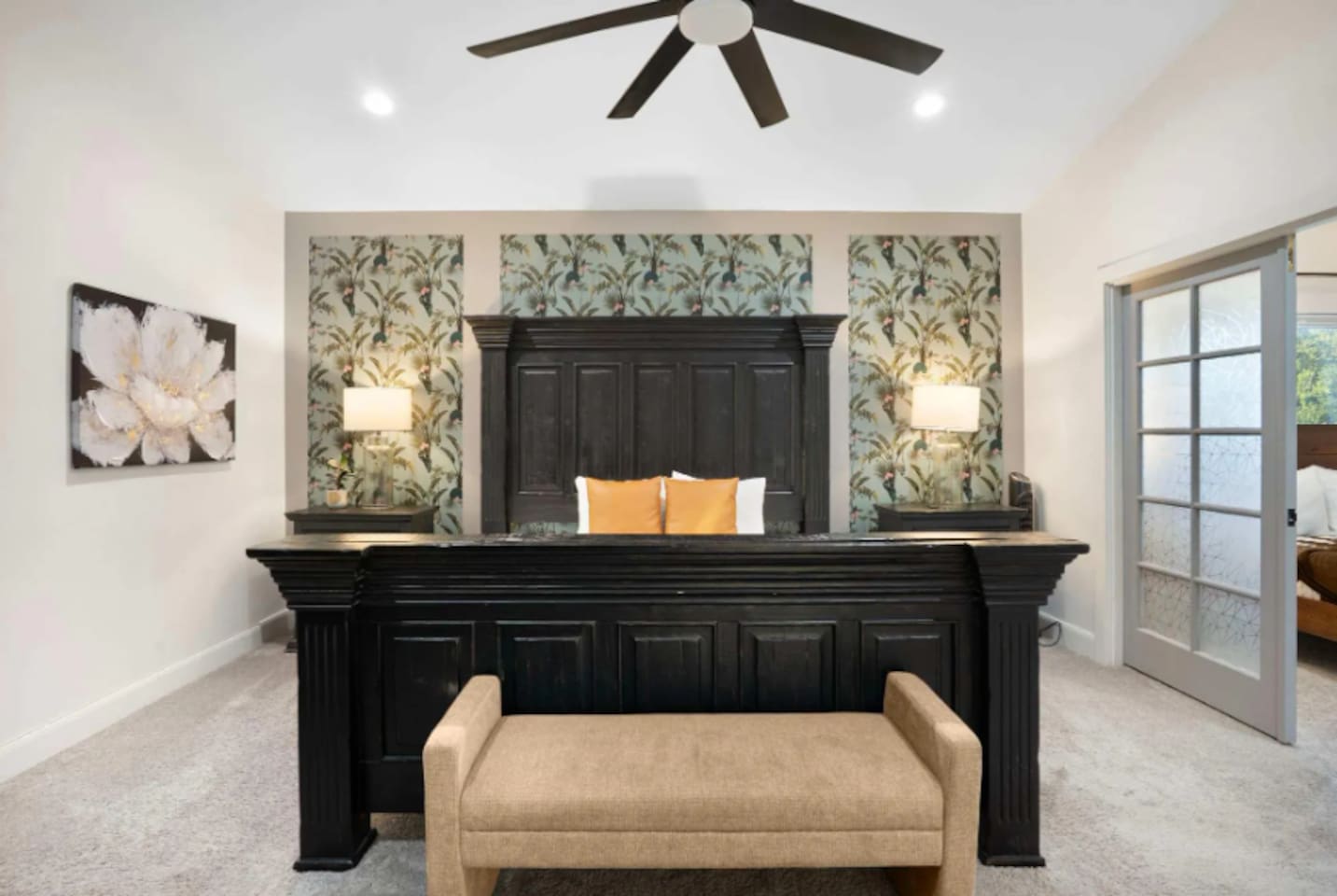 Stunning master suite with statement black bed frame, botanical wallpaper accent wall, and spa-like ensuite.