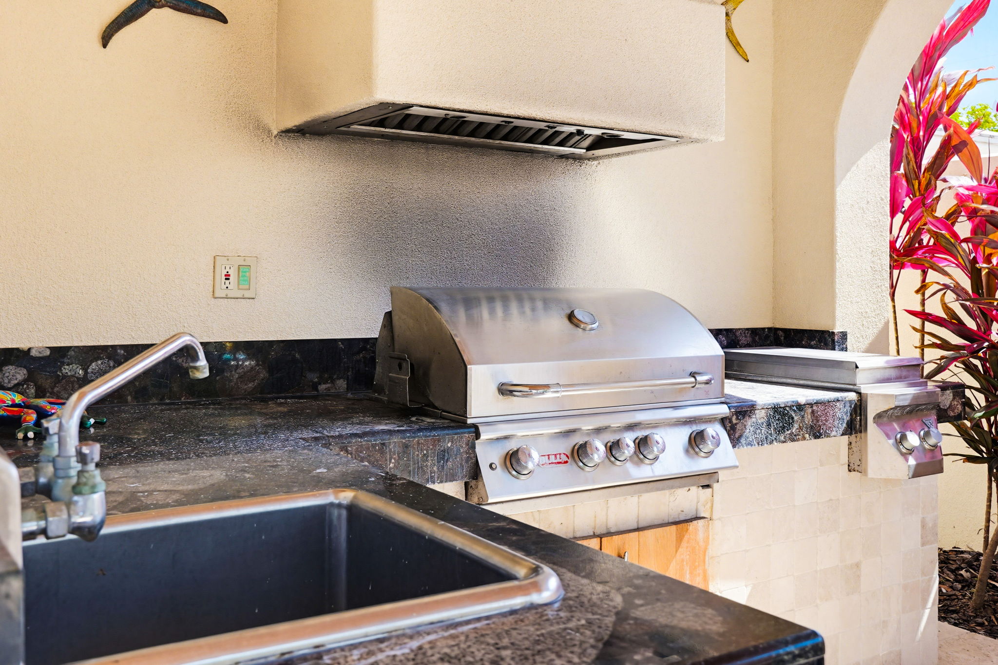 An outdoor kitchen, complete with a built in grill and range hood.