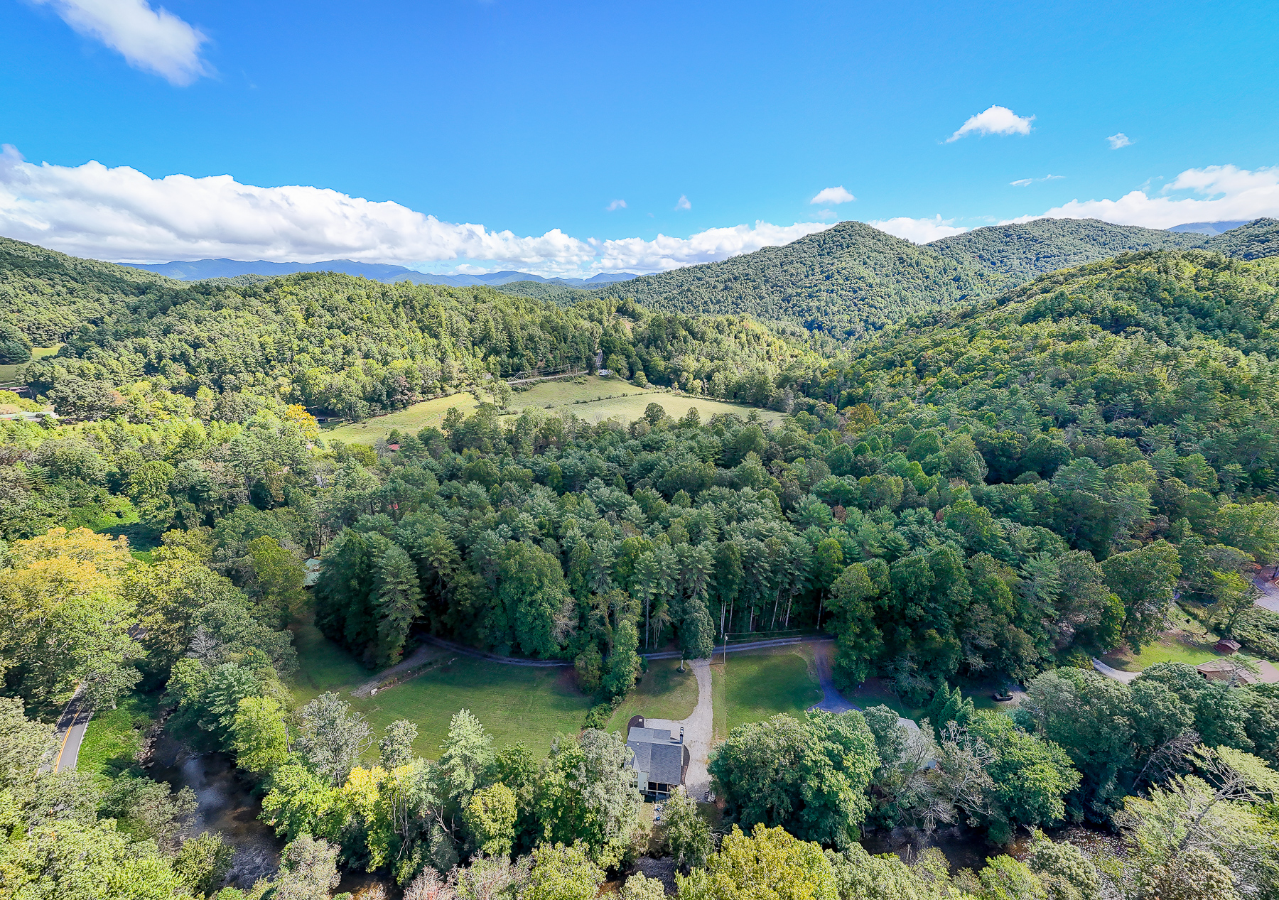 An aerial look at Robbin’s Nest on Snowbird Creek and its creekside setting, surrounded by wooded hills and the mountains of Western North Carolina.