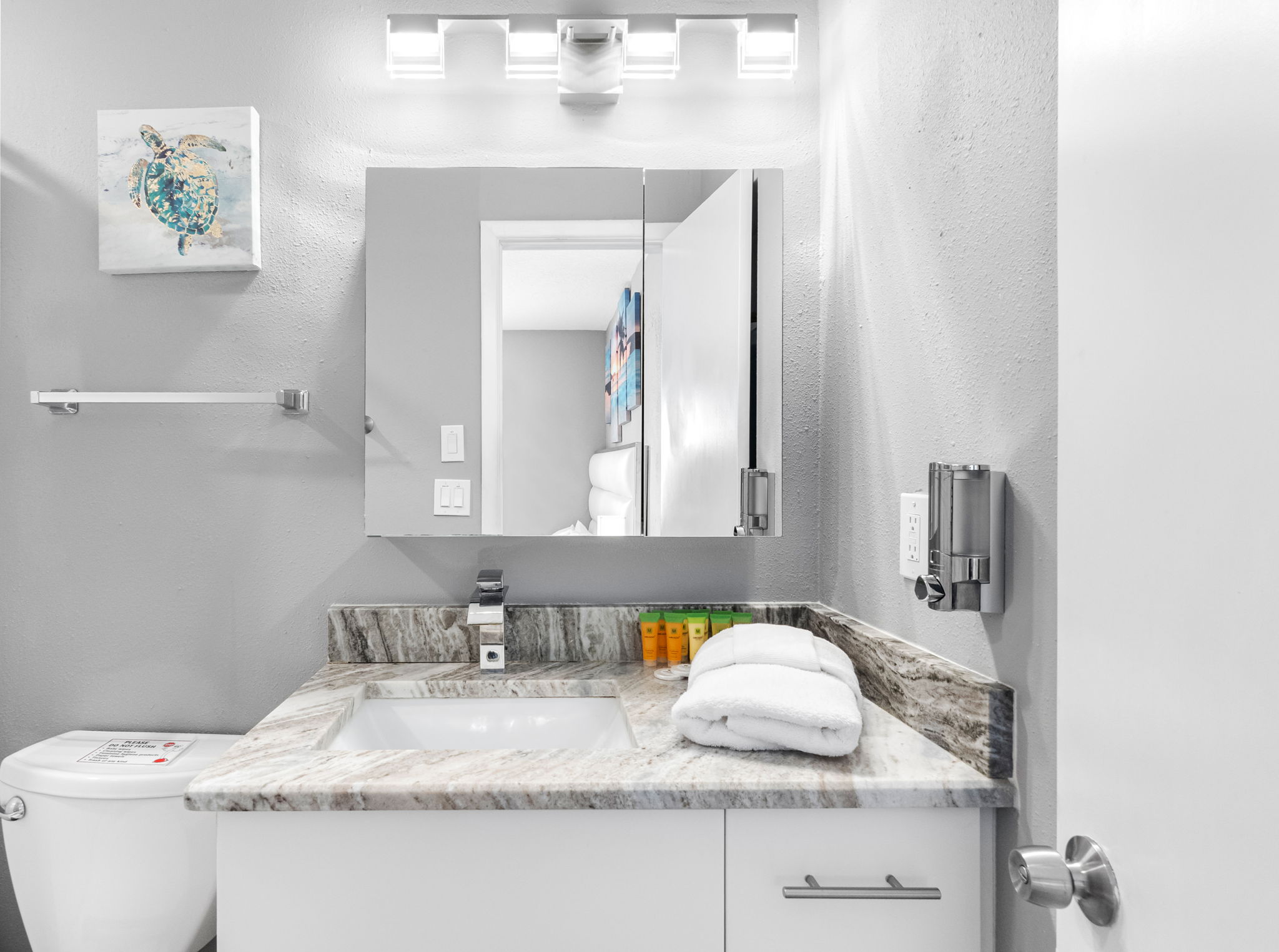 This bathroom features a calming gray palette, illuminated vanity mirror, and polished chrome fixtures to create a serene atmosphere.