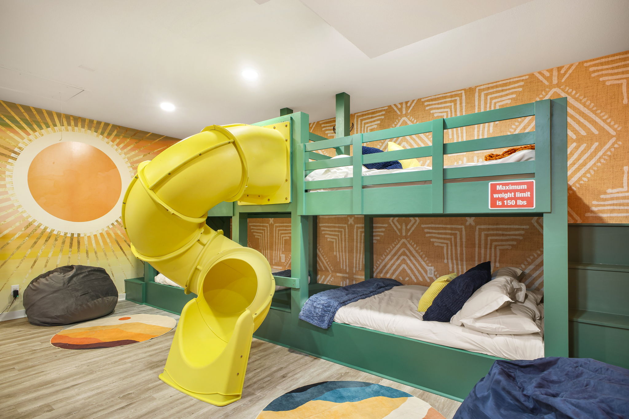 Bedroom 5 / Games Room: Playful yellow slide for kids, comfy bean bags, colorful murals, and bunk room fun. 