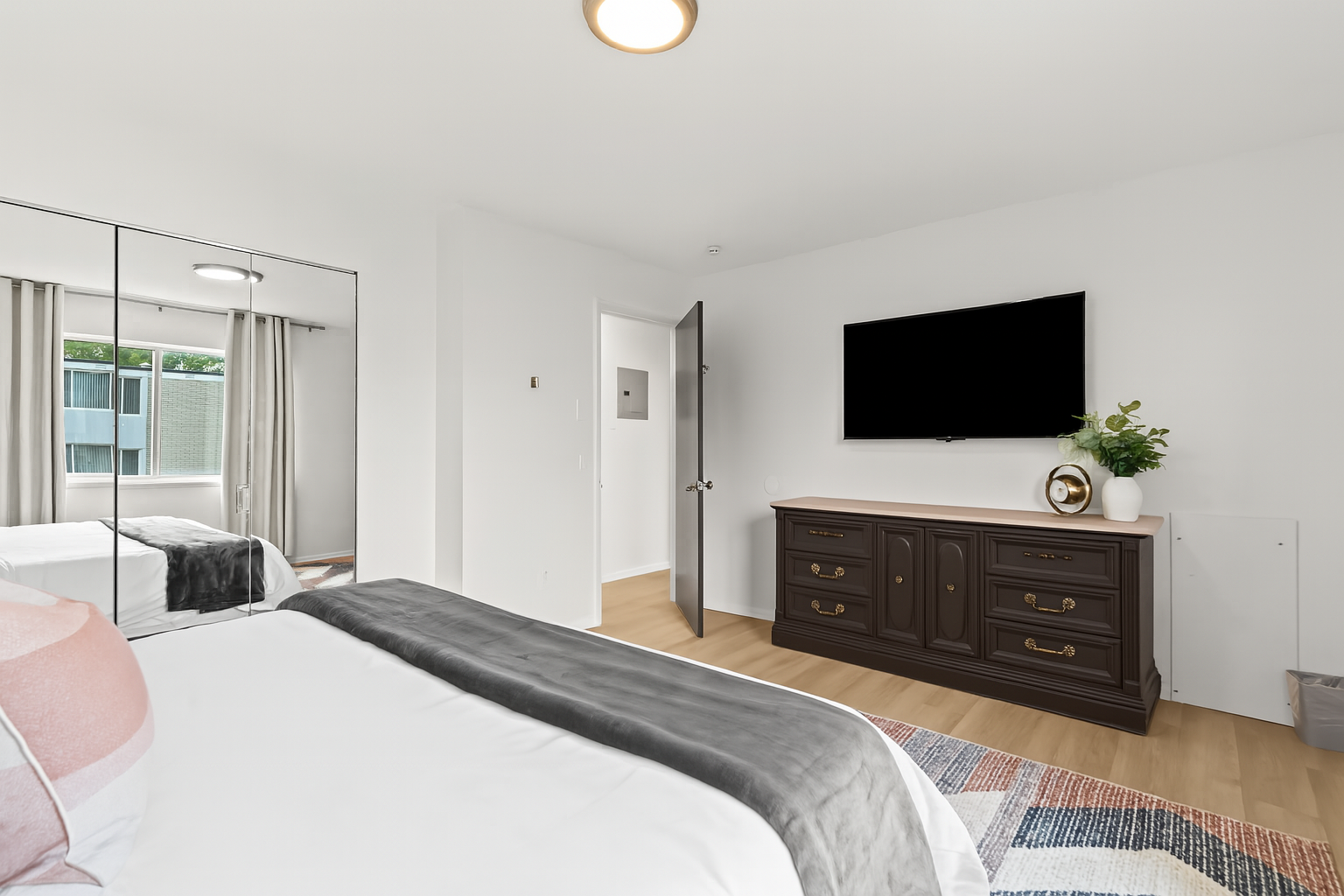 Spacious bedroom with Smart TV, dresser, and plenty of natural light for your comfort.