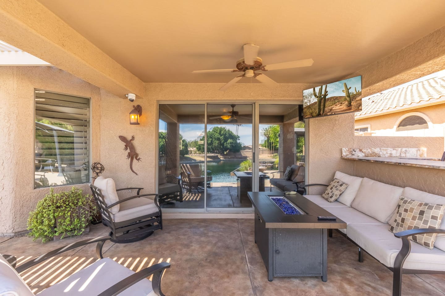 The covered patio seamlessly connects indoor and outdoor living — step through the sliding glass doors from the living room and settle into the cushioned seating around the fire table.