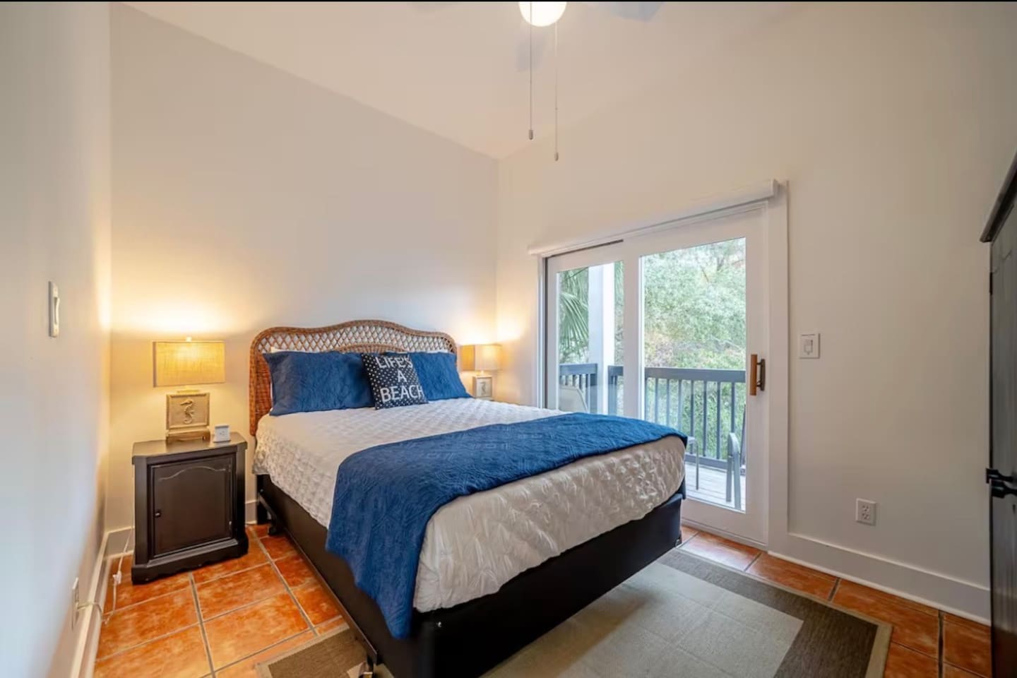 Main floor bedroom with queen bed and private balcony overlooking wooded area