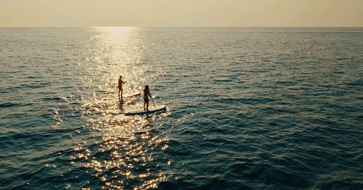 Couple paddleboarding into the Gulf off Manasota Key, Florida.